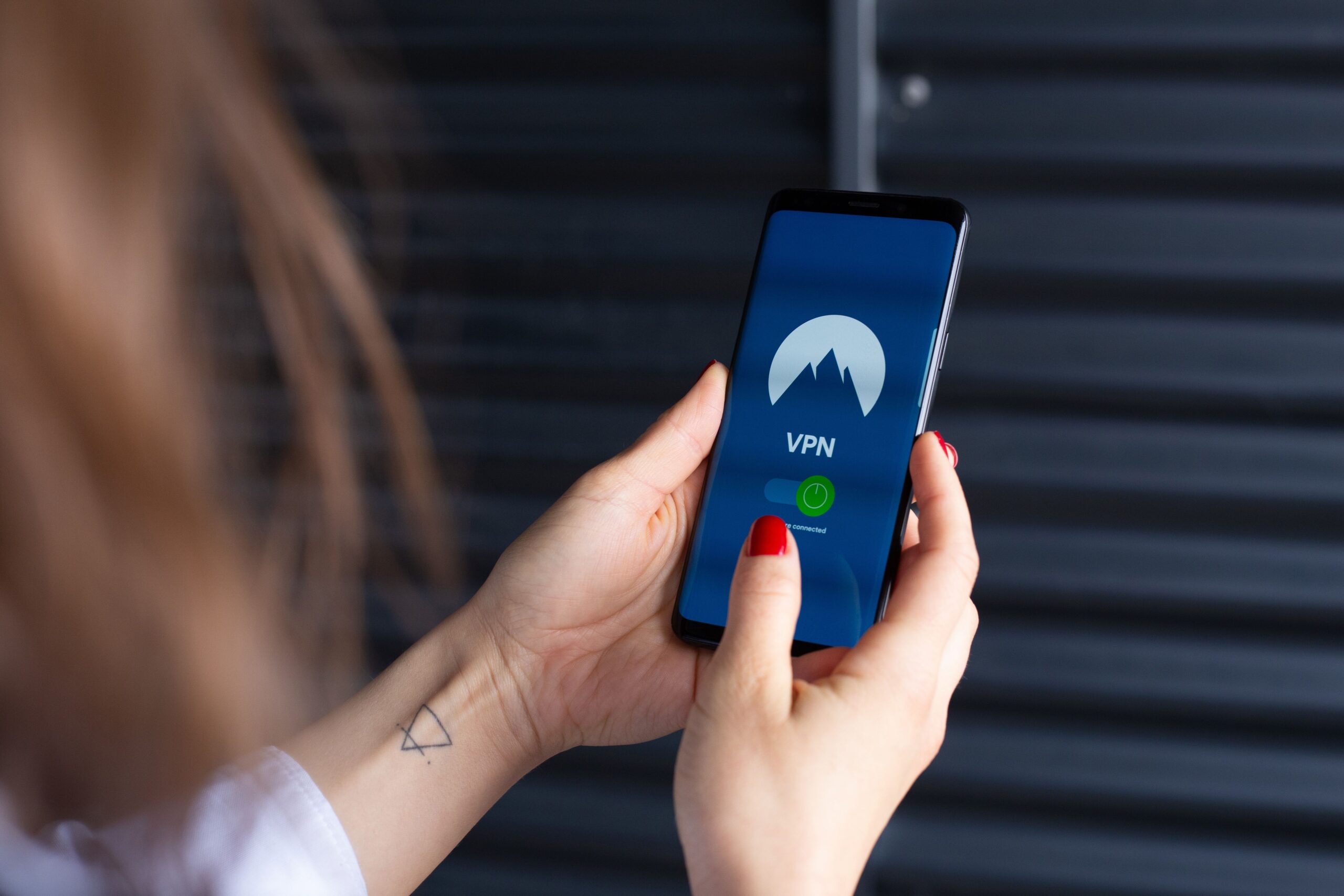 Persona utilizando una aplicación de conexión segura en su smartphone para acceder a recursos remotos de forma privada.