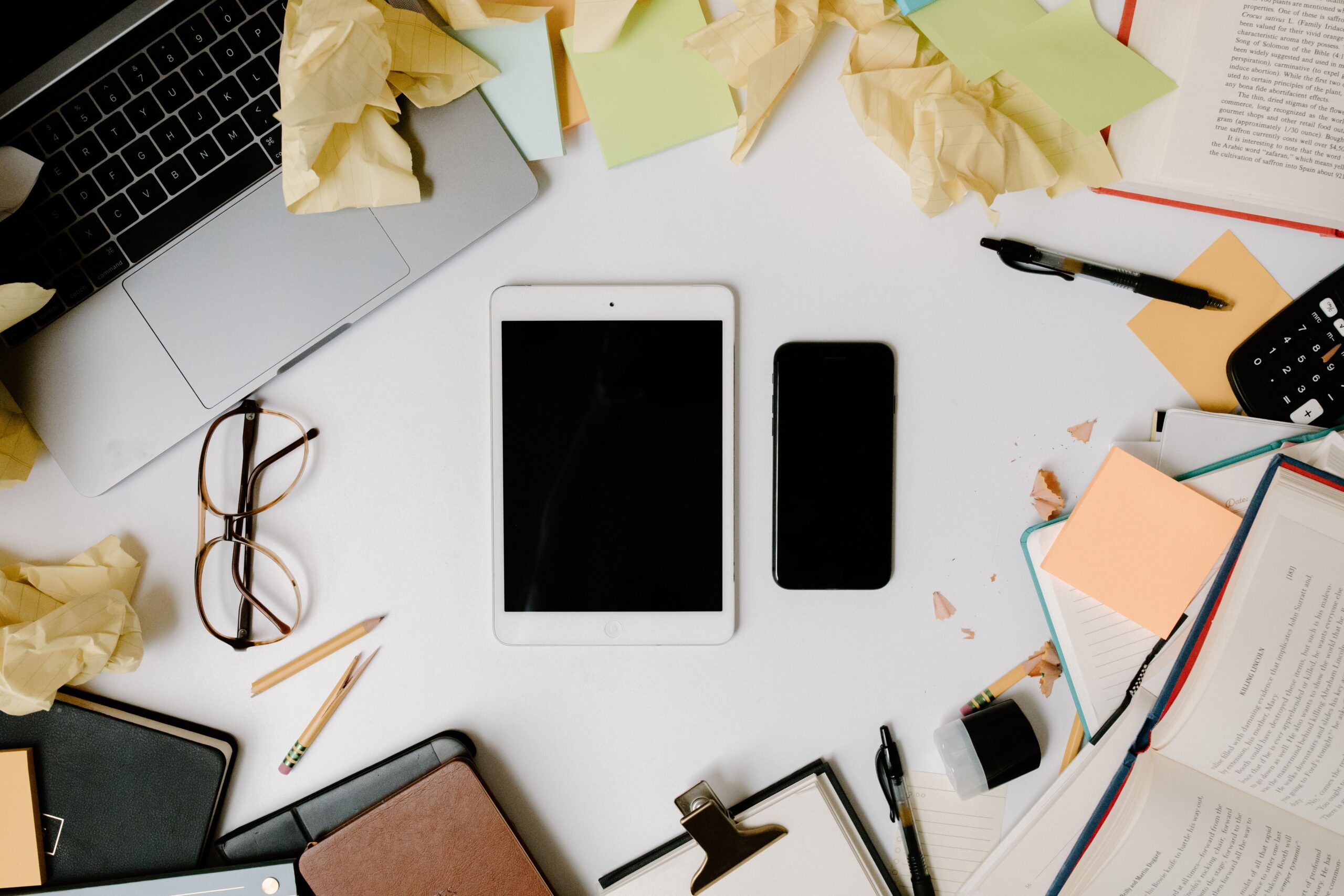 Vista cenital de un escritorio moderno organizado con dispositivos digitales y papelería, simbolizando la eficiencia y la organización de la información digital.