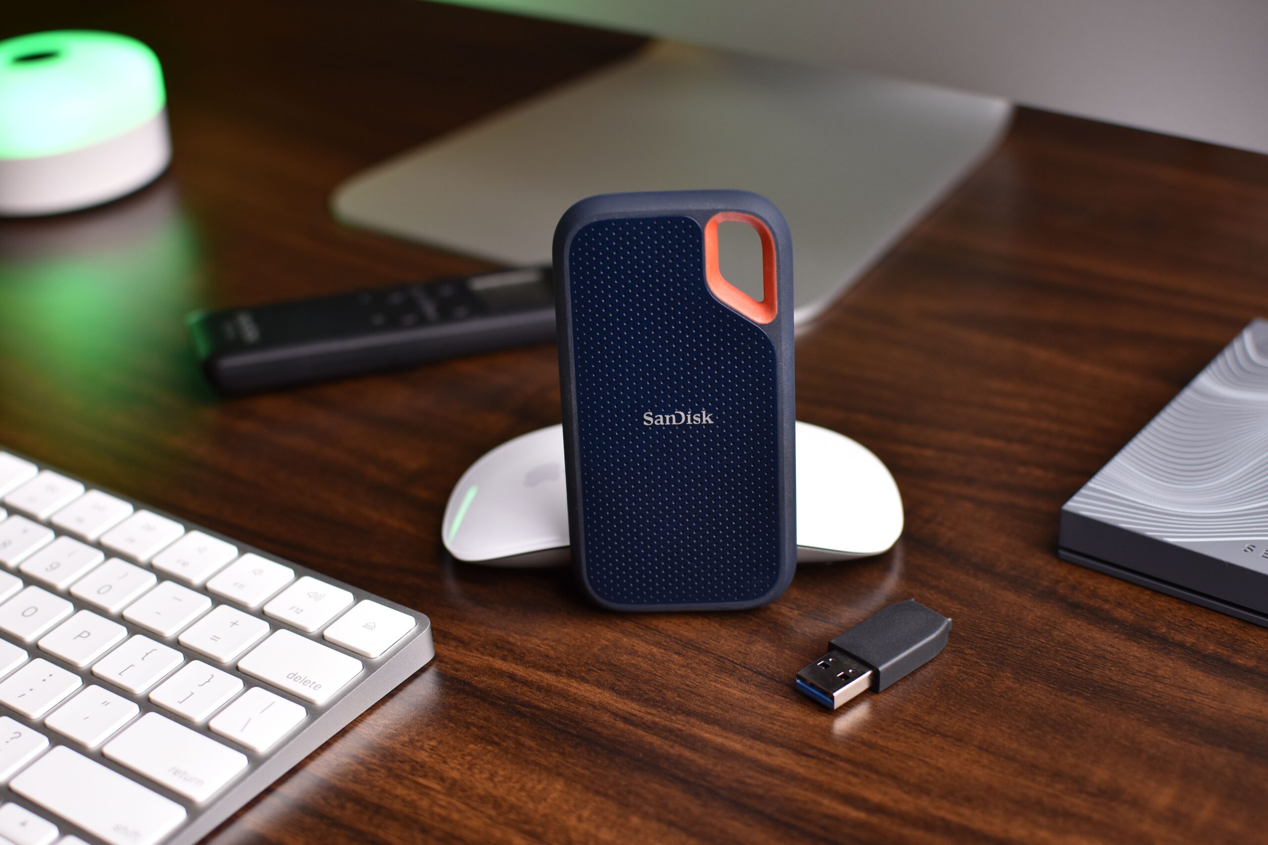 Primer plano de un SSD portátil de alto rendimiento y accesorios informáticos en un entorno profesional.