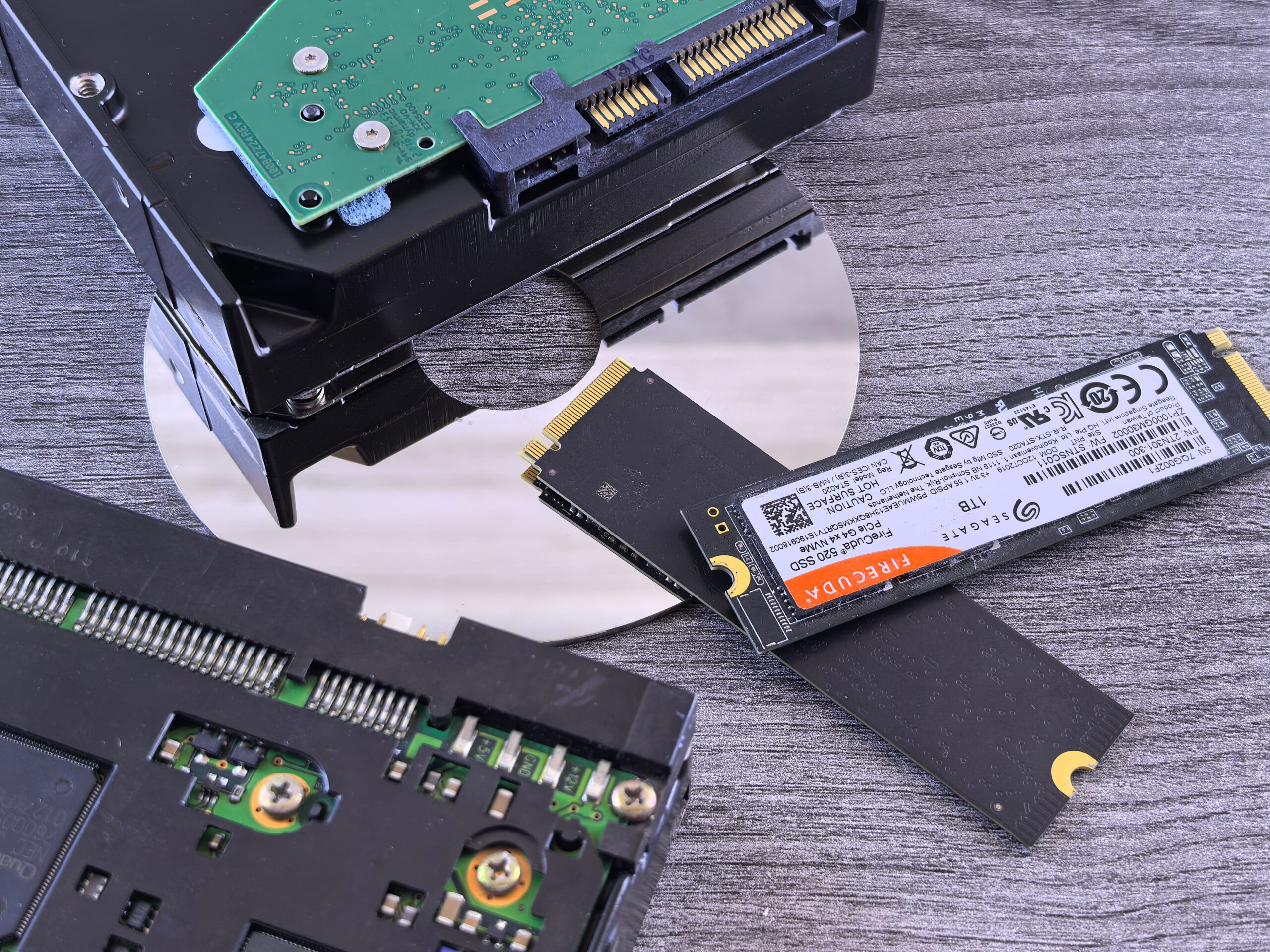 Comparativa visual entre un SSD NVMe, un disco duro HDD y un CD.