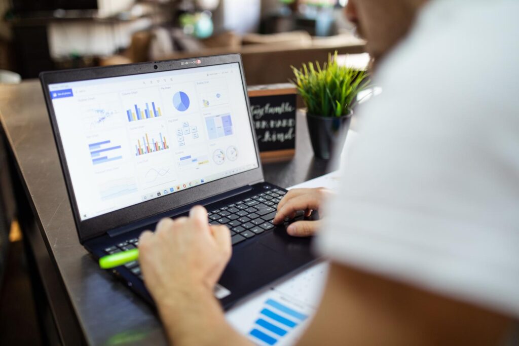 Profesional analizando un dashboard de gráficos coloridos en un ordenador portátil en una oficina moderna.