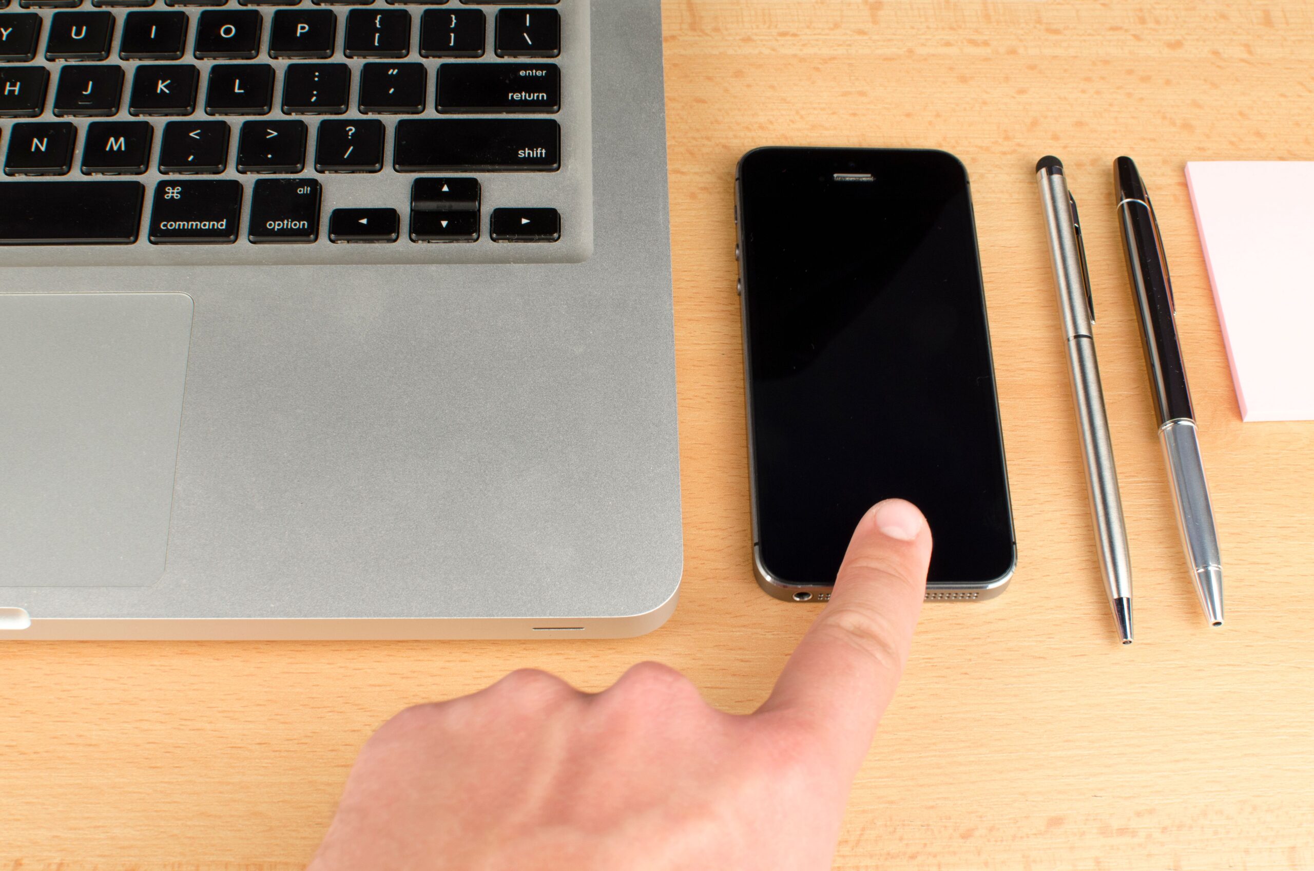 Espacio de trabajo moderno con un portátil y un smartphone, sugiriendo un flujo de trabajo digital coordinado.