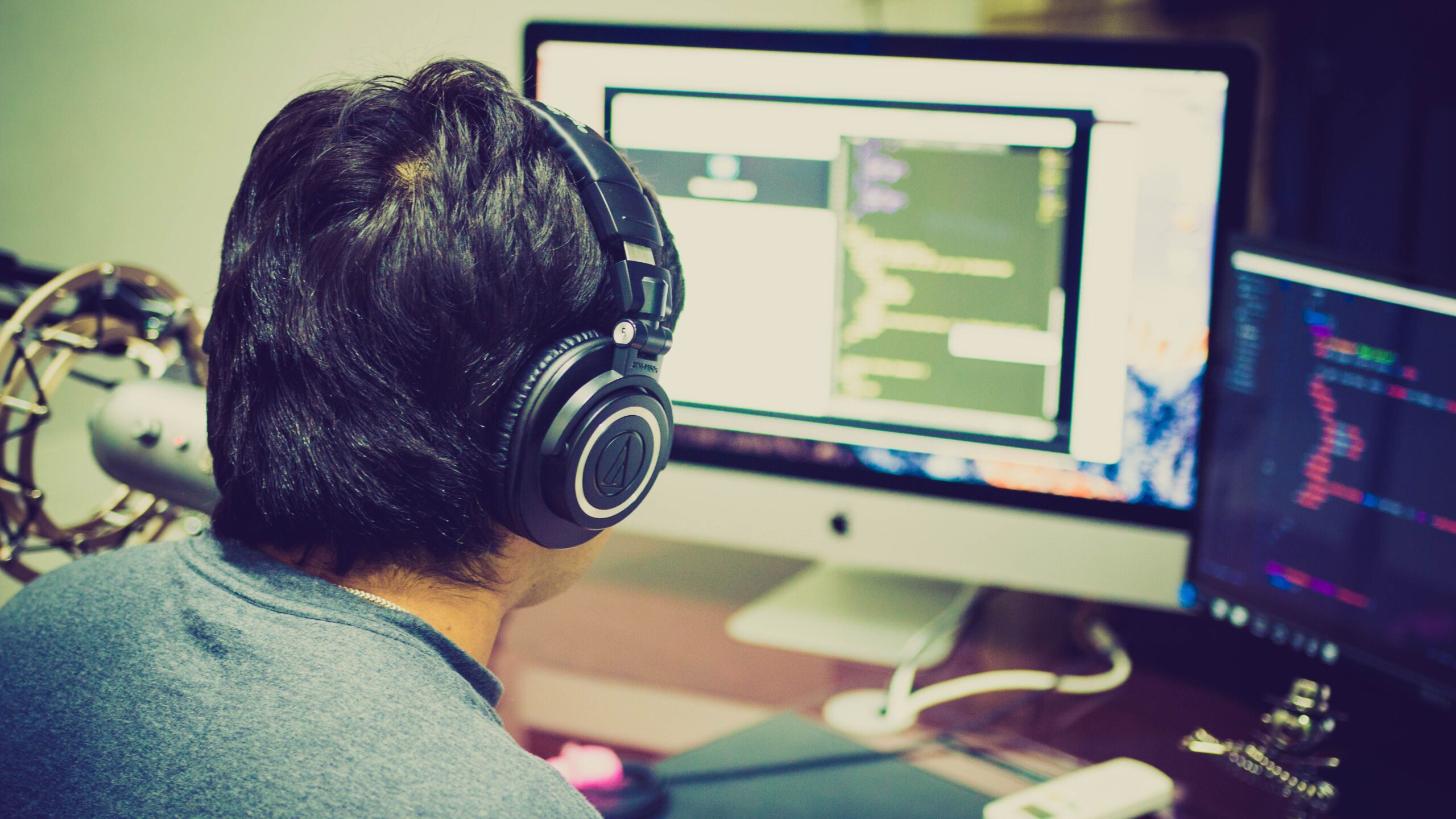 Programador concentrado trabajando en un entorno de desarrollo profesional con configuración de monitores duales.