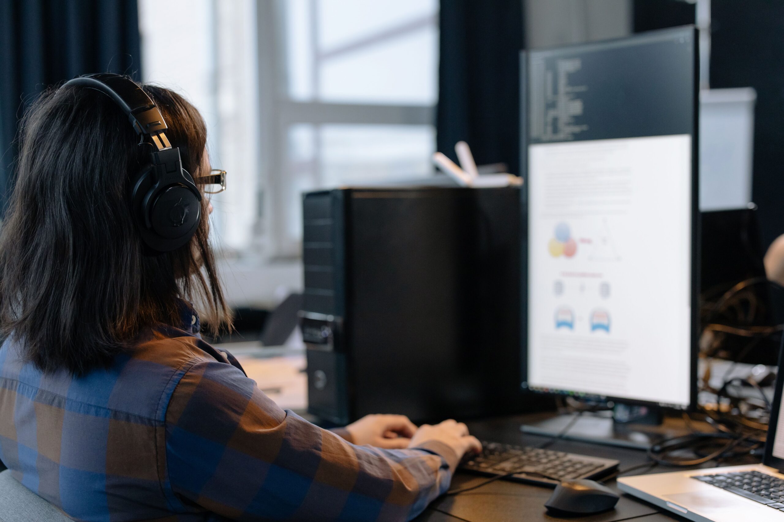 Profesional de IT trabajando con un monitor vertical, optimizando su flujo de trabajo de programación.