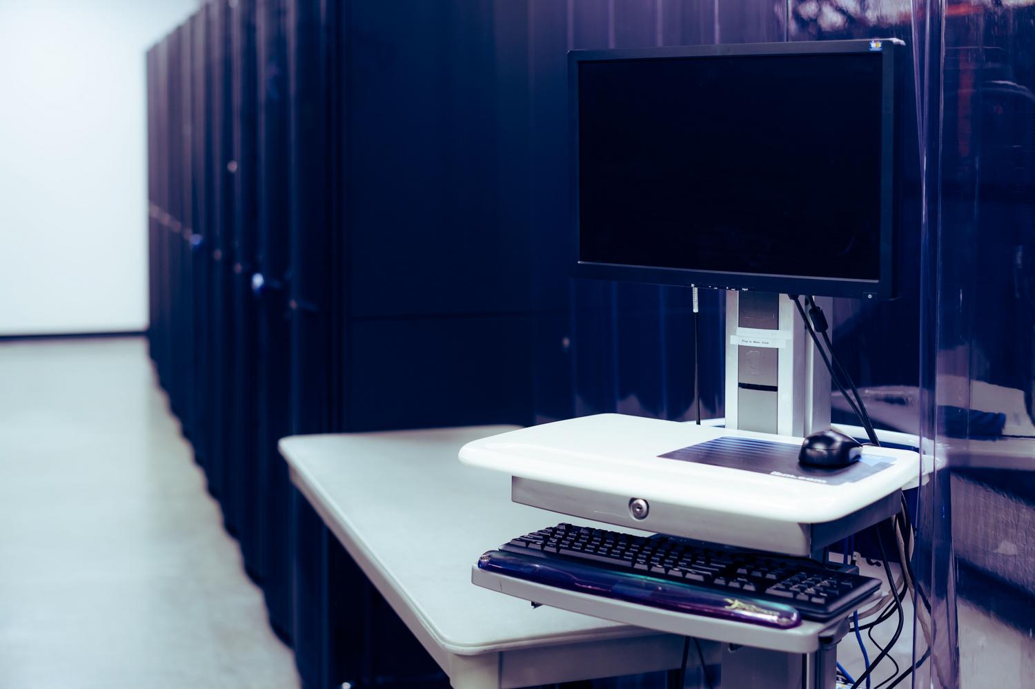 Terminal de administración y monitor frente a una fila de servidores en un centro de datos