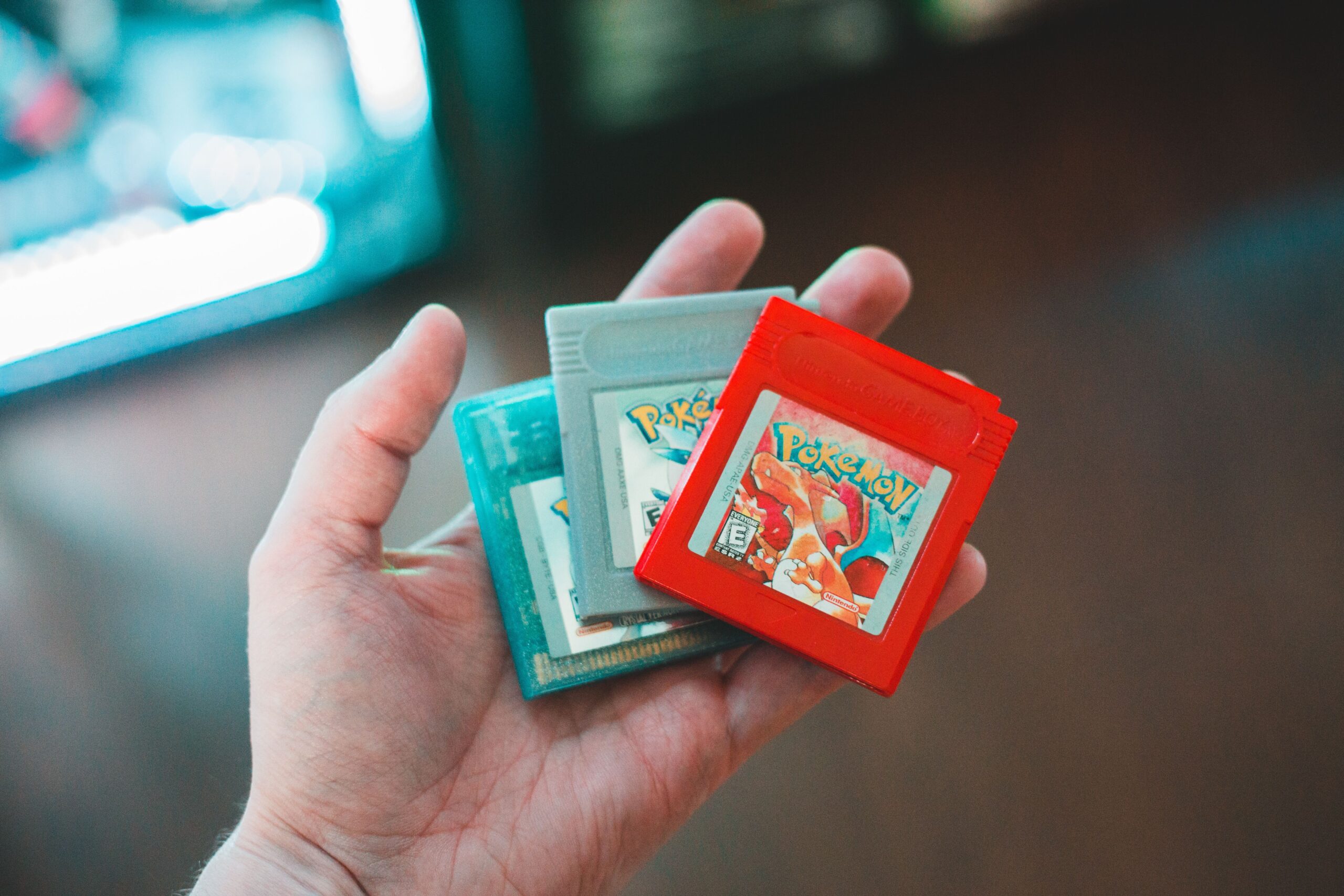 Primer plano de una mano sosteniendo cartuchos de juegos clásicos de Pokémon, representando la curación de una colección.