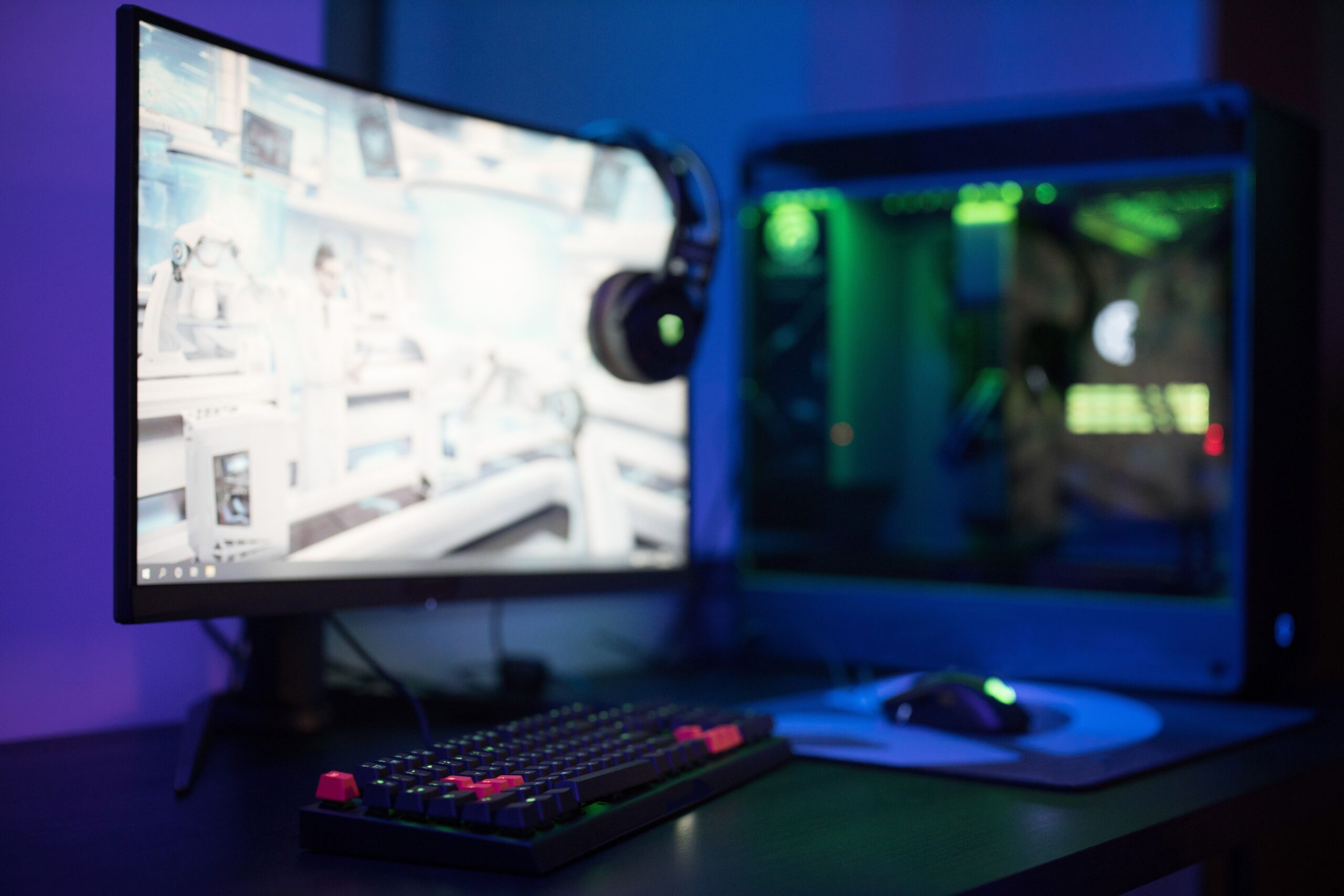 Setup de gaming moderno y tecnológico con monitor curvo, teclado RGB y ambiente iluminado.