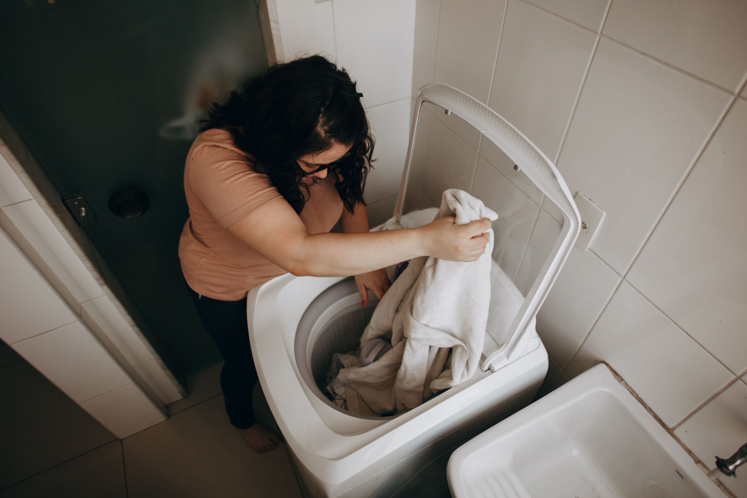 Mujer cargando ropa en una lavadora en un entorno doméstico cotidiano