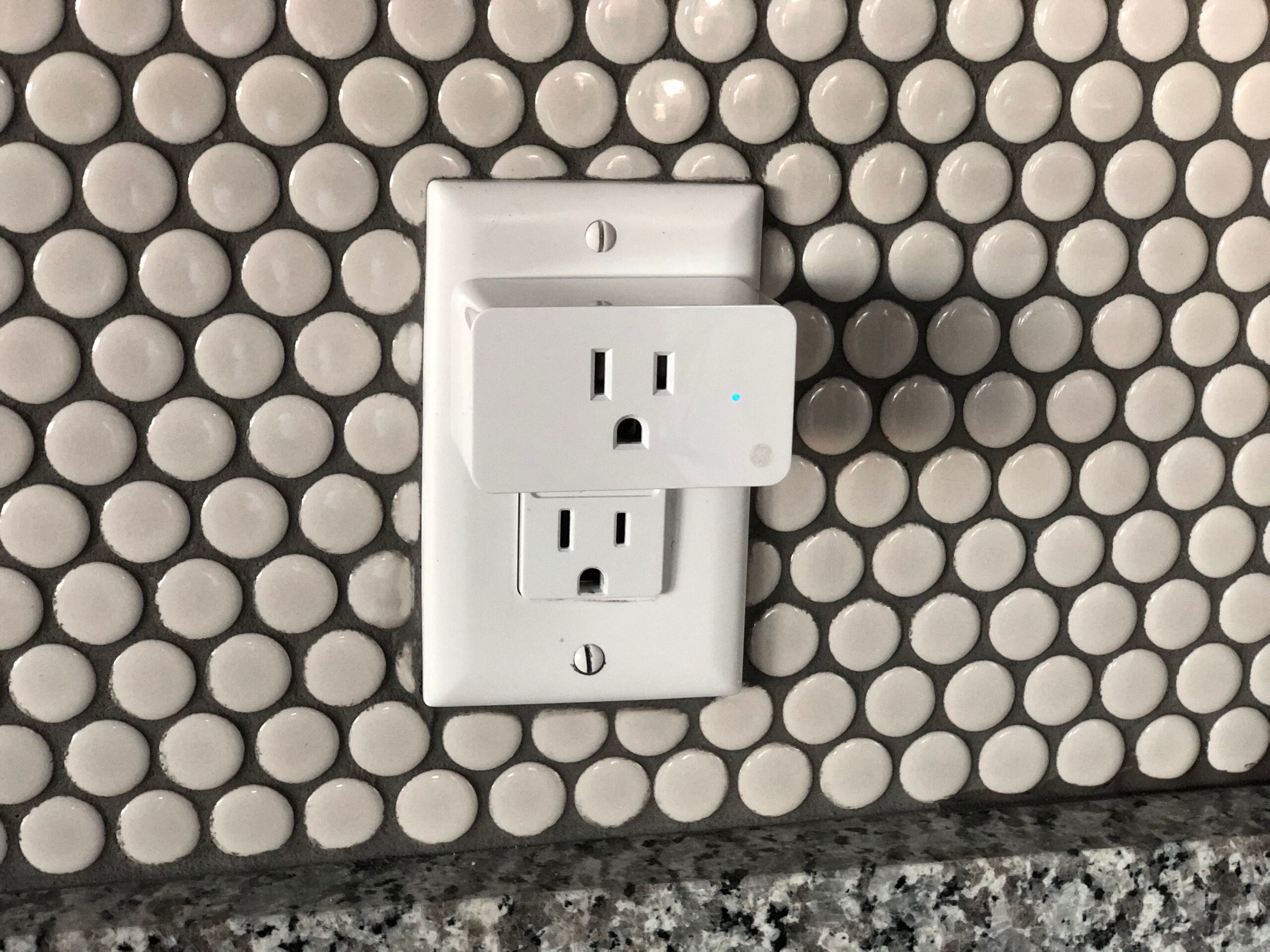Primer plano de un enchufe inteligente conectado a la pared con indicador LED azul