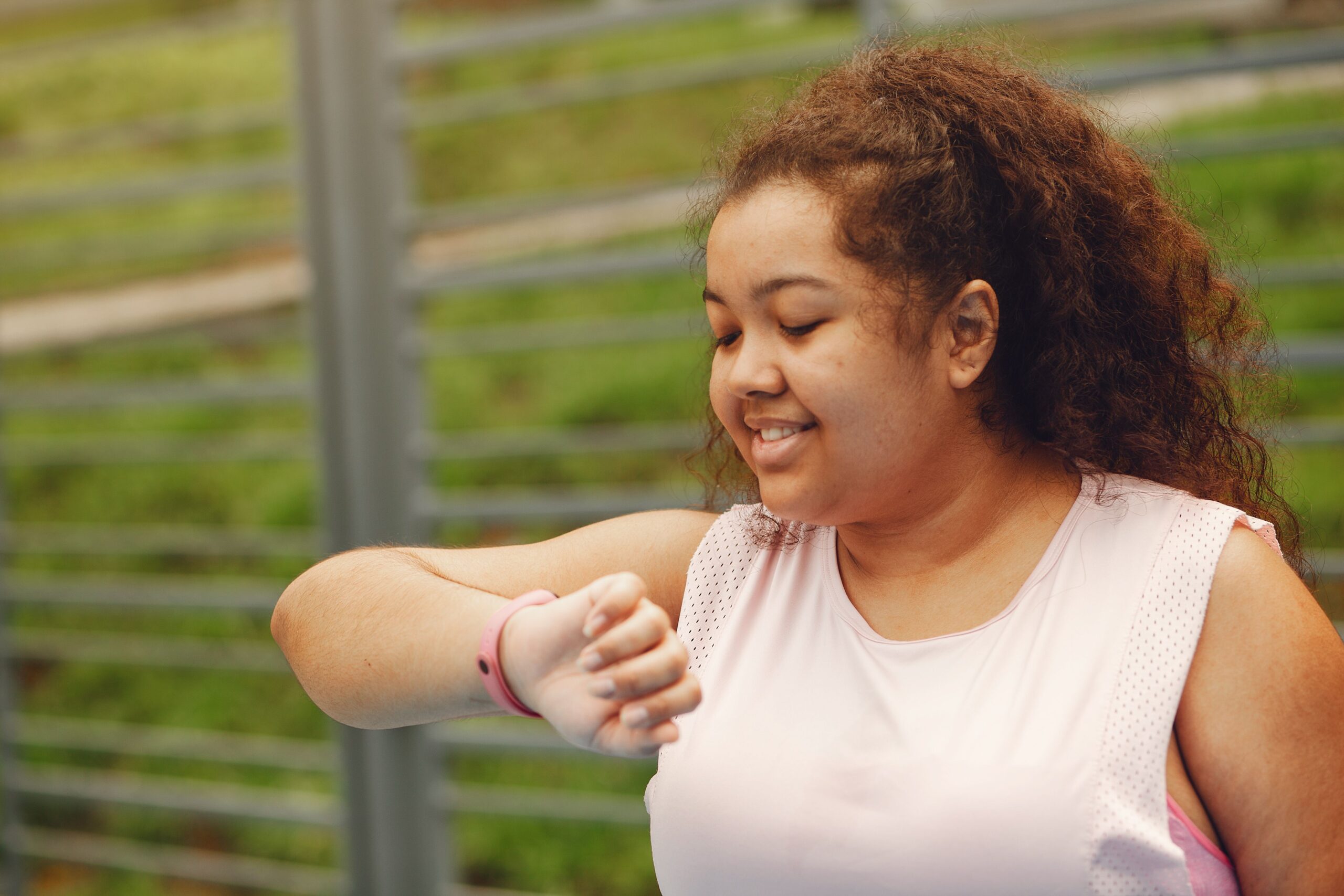 Mujer sonriente consultando su reloj inteligente al aire libre, reflejando la satisfacción de mantener su historial de actividad.