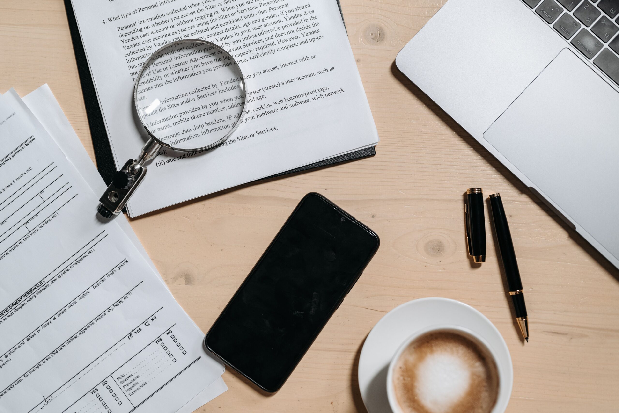 Vista cenital de un escritorio con documentos y una lupa, ilustrando la auditoría manual de resolución y legibilidad antes del procesamiento OCR.