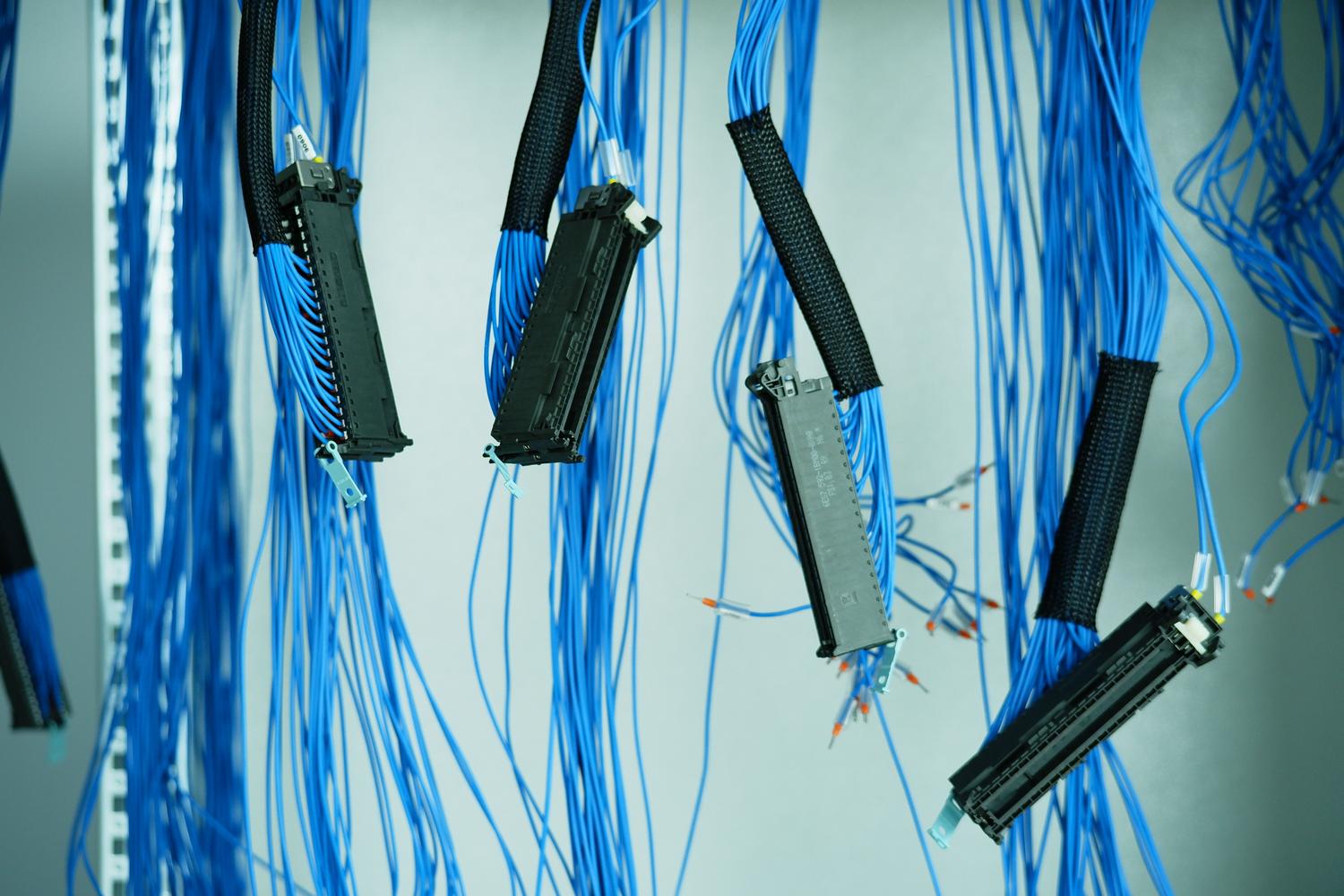 Primer plano de cables de red azules colgando en un centro de datos, representando la conectividad física y los flujos de datos entre aplicaciones.