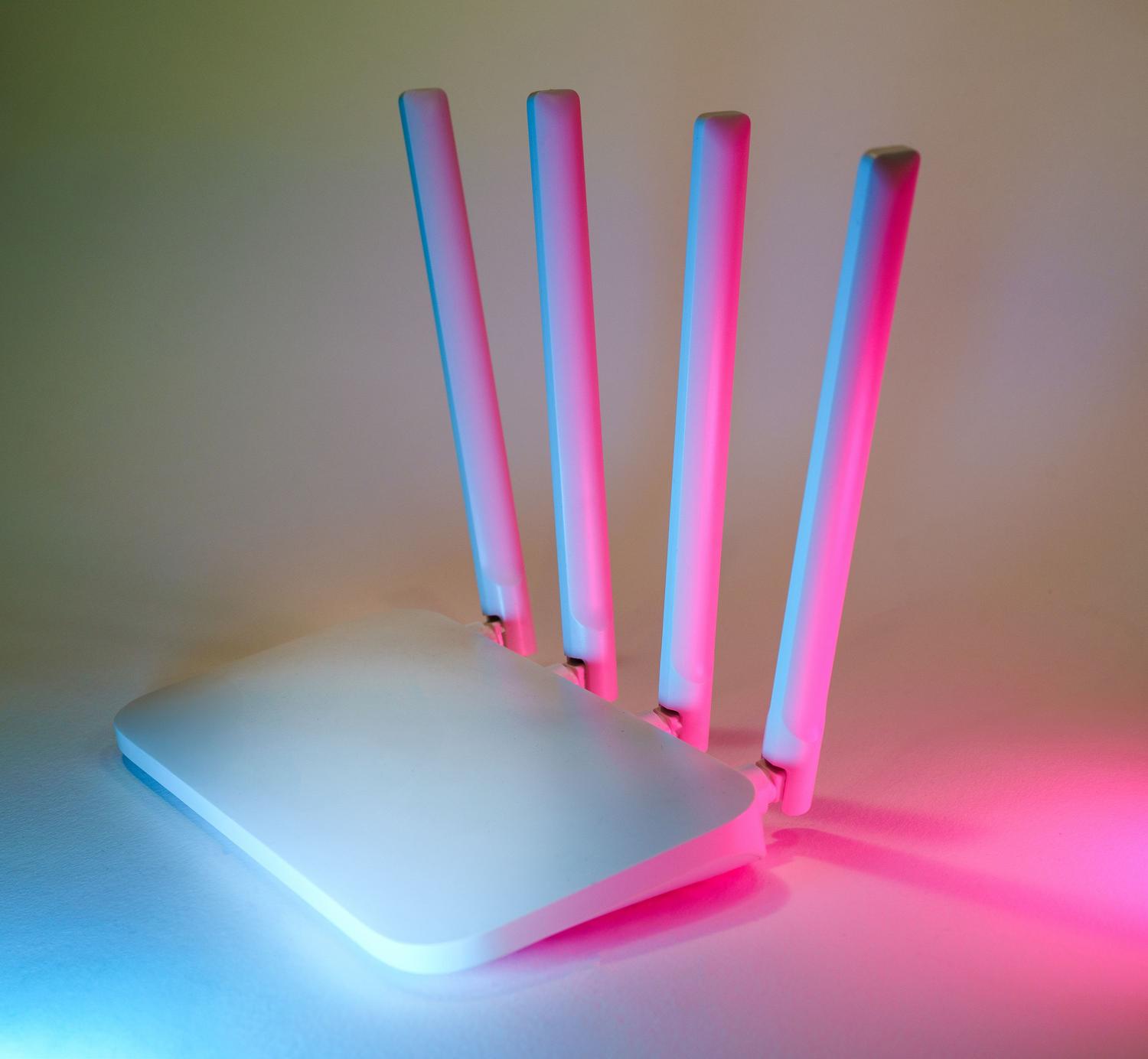 Router inalámbrico moderno con iluminación neón cian y rosa, representando la infraestructura digital y la velocidad de conexión de las herramientas SaaS.