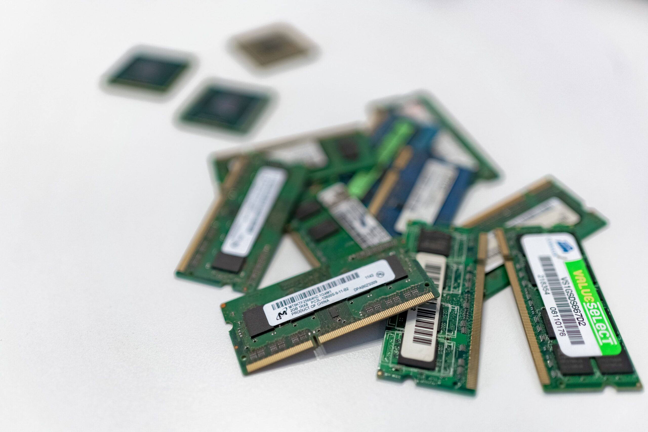 Varios módulos de memoria RAM de diferentes generaciones y capacidades esparcidos sobre una superficie blanca, ilustrando la incompatibilidad.
