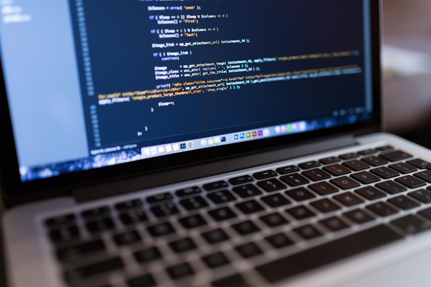 Programador trabajando con un portátil y café, centrado en el código de la pantalla