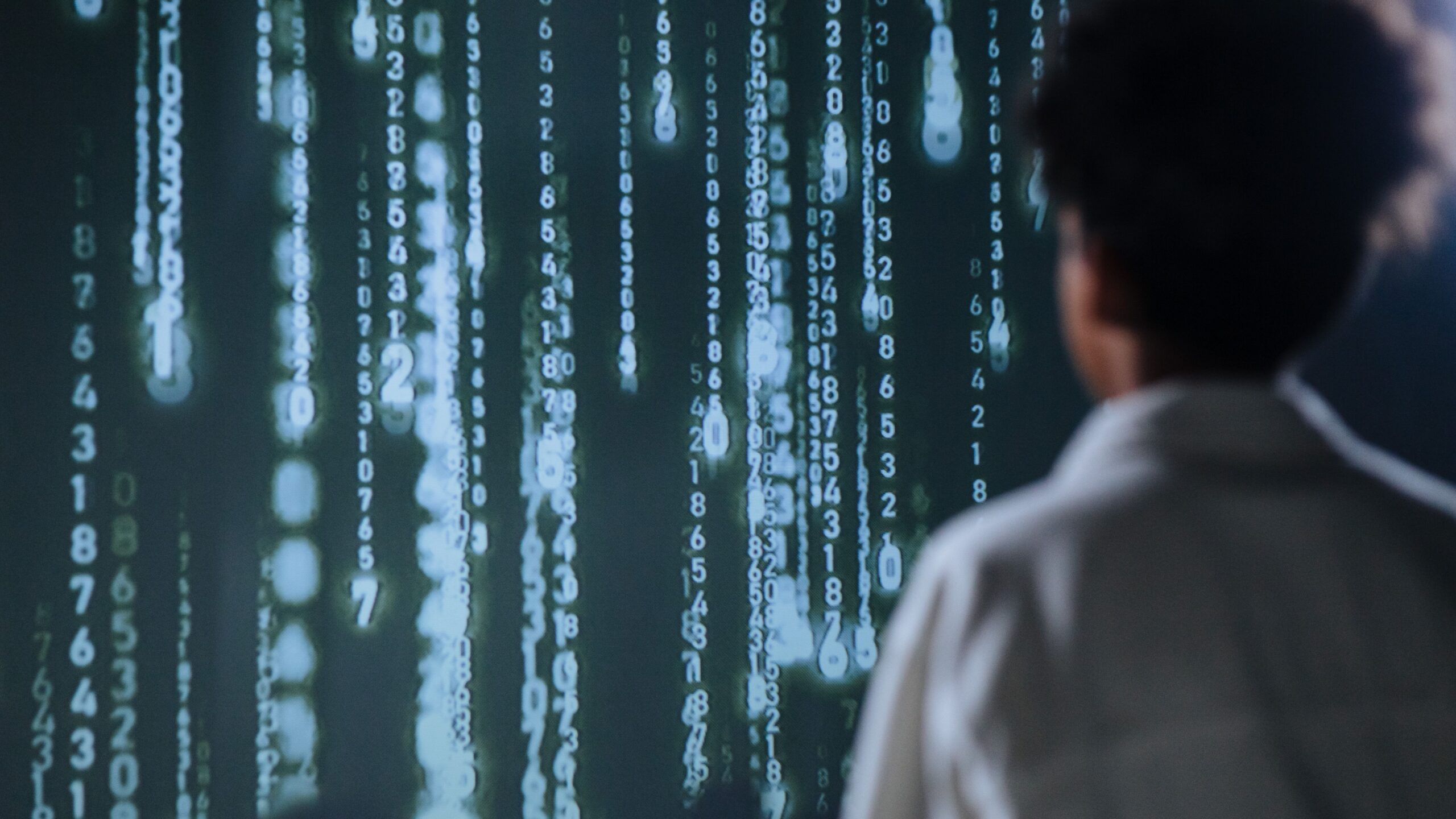 Persona analizando una cascada de datos numéricos en una pantalla, representando el ajuste técnico y el monitoreo de rendimiento de un software.