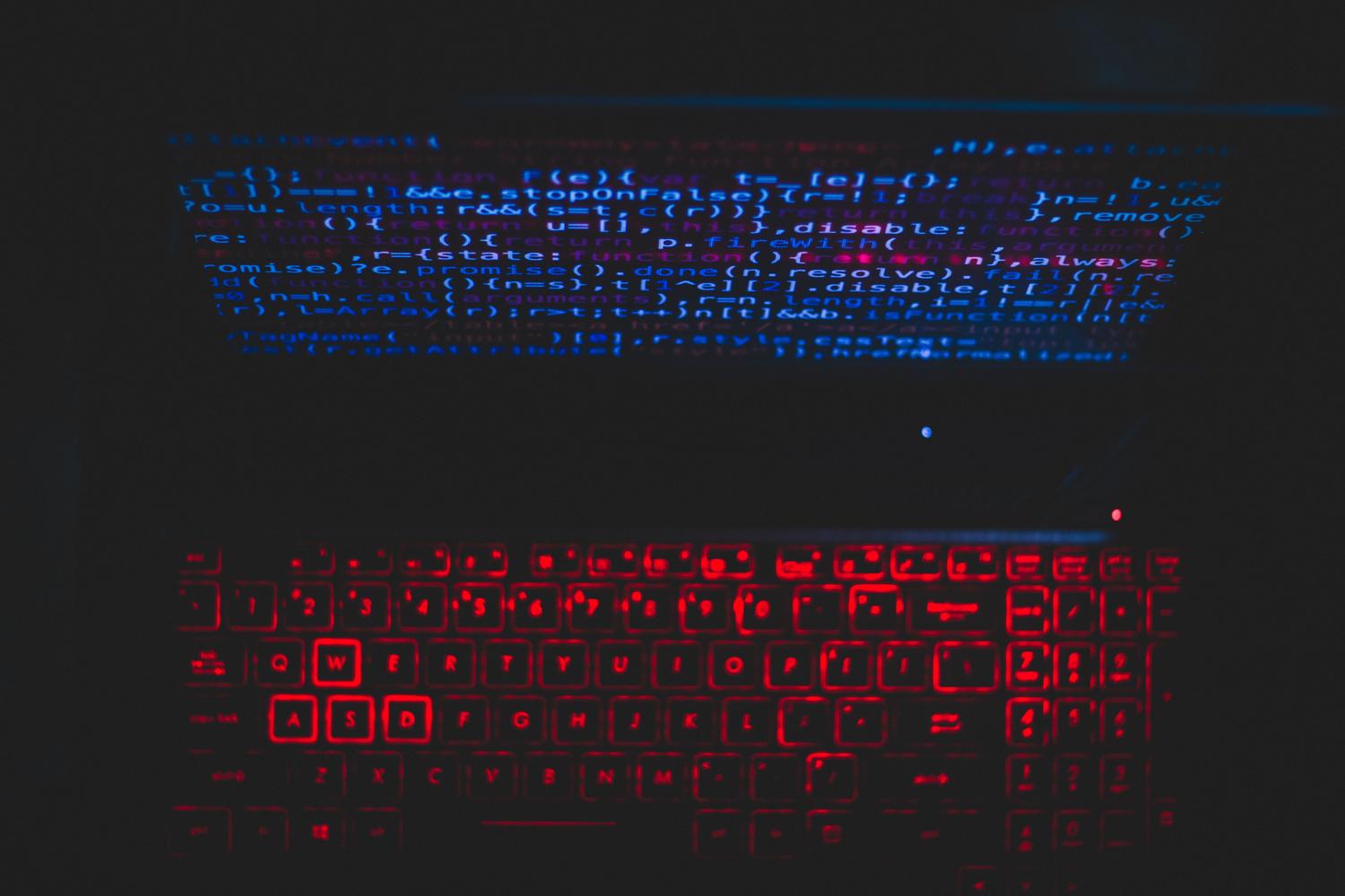Setup de programación con teclado iluminado y código en pantalla, ideal para reflejar la productividad técnica.