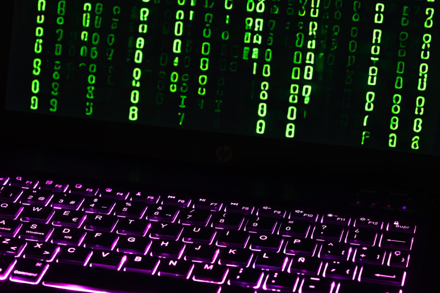 Teclado de laptop iluminado con código estilo Matrix en pantalla, representando el software de código abierto y la configuración técnica.