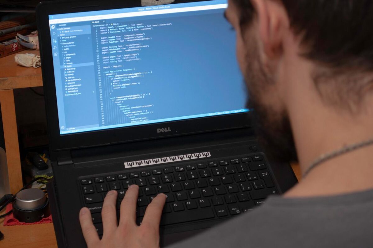 Desarrollador programando en Visual Studio Code en un portátil en entorno de oficina
