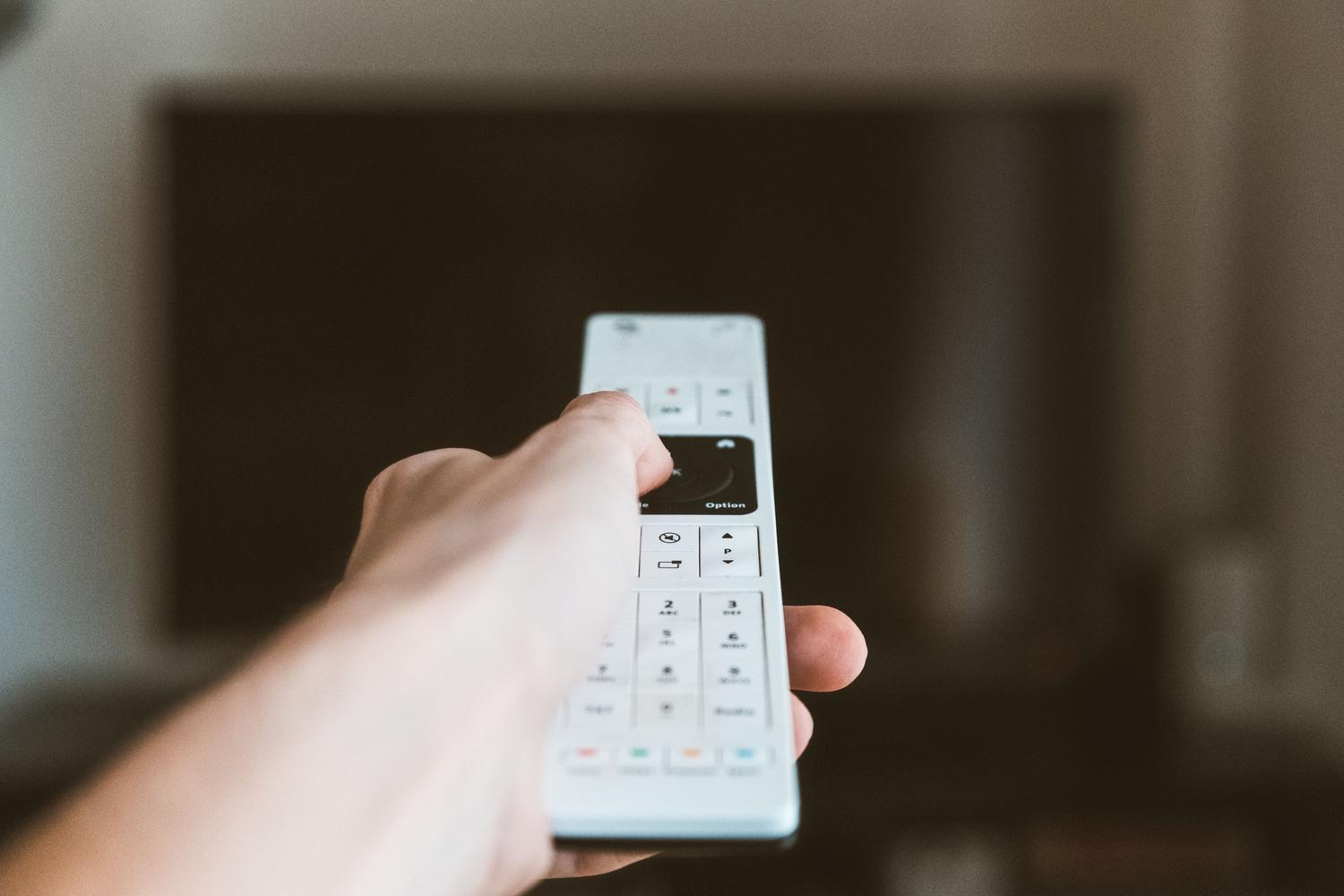 Primer plano de una mano utilizando el mando a distancia de la televisión