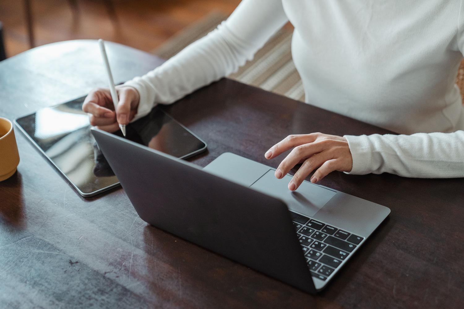 Mujer de negocios trabajando con tablet y laptop, ilustrando un flujo de trabajo productivo y sin fricciones.