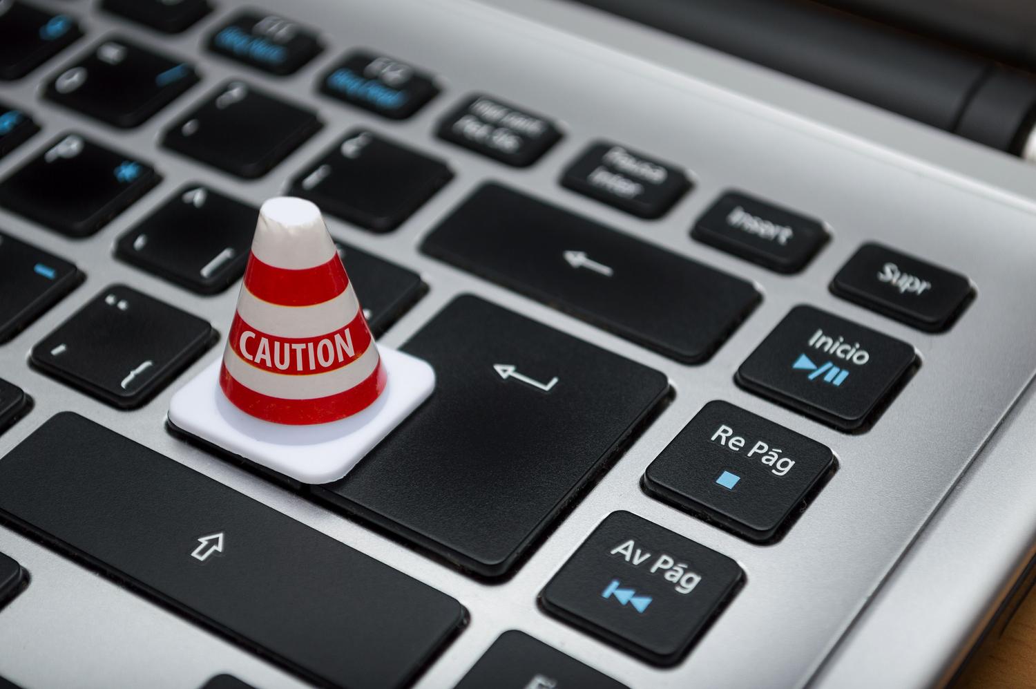 Miniatura de un cono de precaución sobre un teclado de ordenador, metáfora visual sobre el cuidado y riesgo al instalar aplicaciones de origen desconocido.