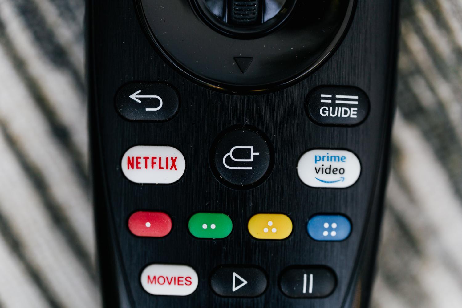 Primer plano detallado de un mando a distancia de televisión, representando la navegación por los menús de configuración del Fire TV.