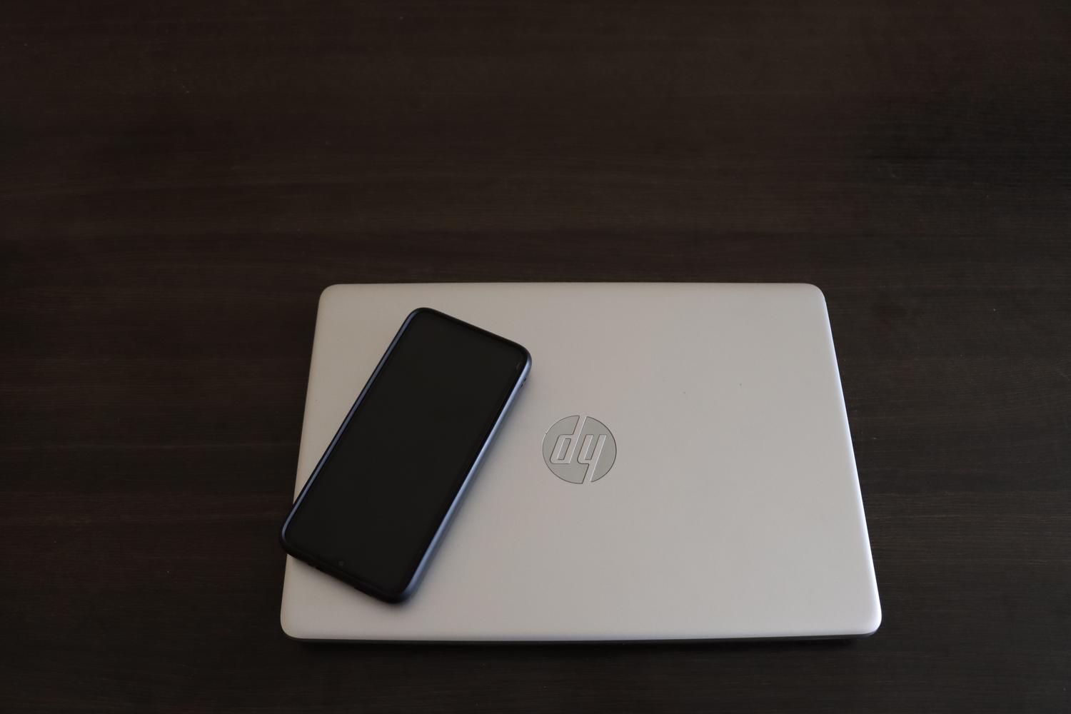 Primer plano de un smartphone apoyado sobre un ordenador portátil, simbolizando la integración técnica entre la mensajería móvil y las herramientas de IA.