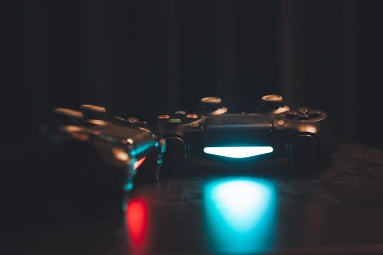 Dos mandos de videojuegos iluminados sobre una superficie oscura, creando una atmósfera de gaming moderna y tecnológica.