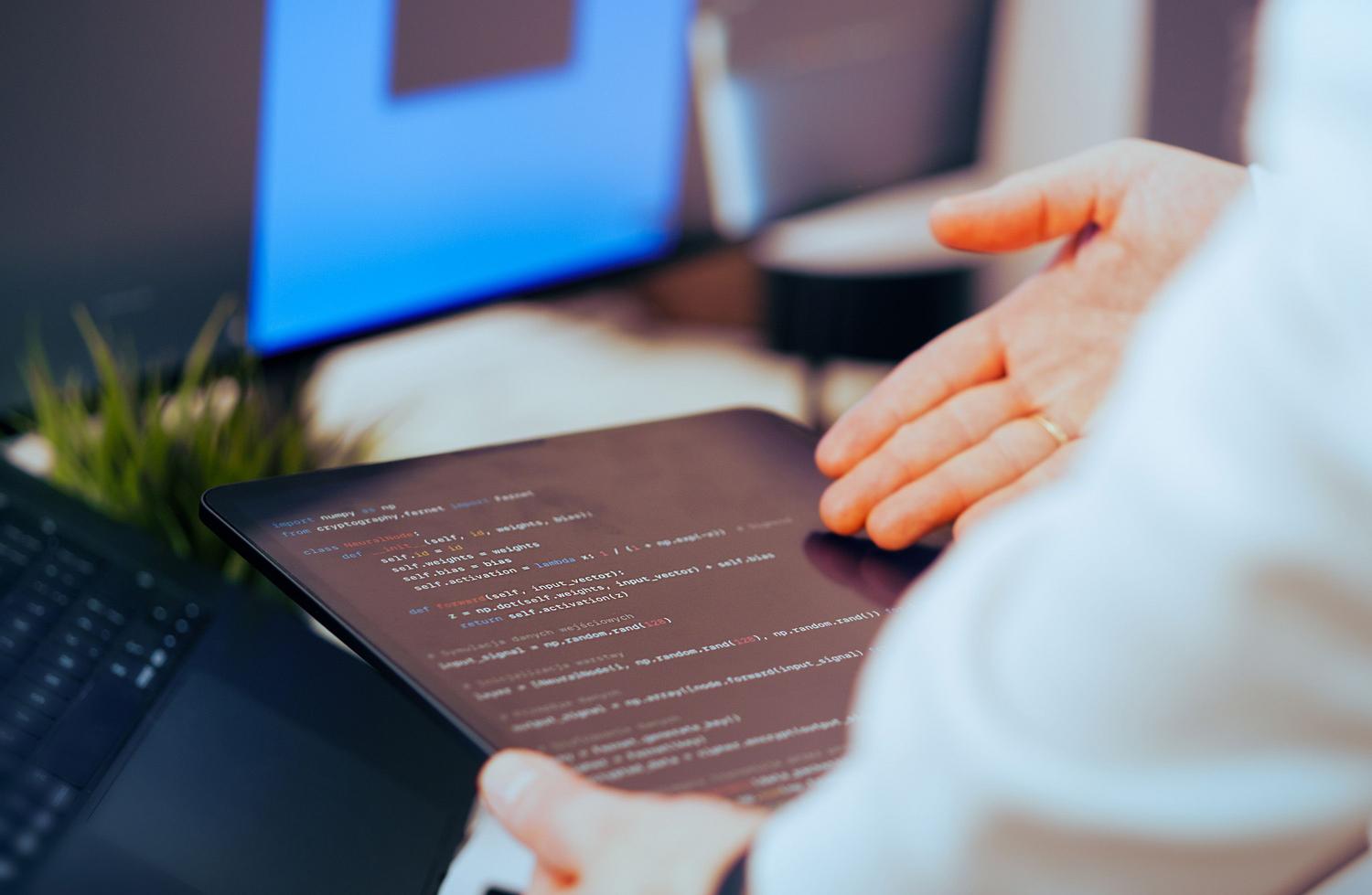 Un développeur examine du code de programmation sur une tablette, illustrant la phase de création et de configuration d'une IA.