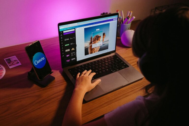 Persona utilizando la herramienta de diseño de Canva en un ordenador portátil dentro de un espacio de trabajo creativo con iluminación moderna.