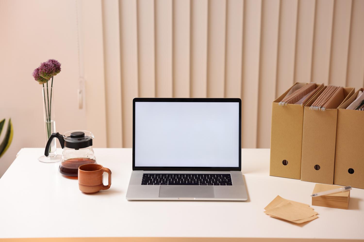 Un espacio de trabajo minimalista con ordenador portátil y organizadores de carpetas, ideal para ilustrar la organización de archivos.
