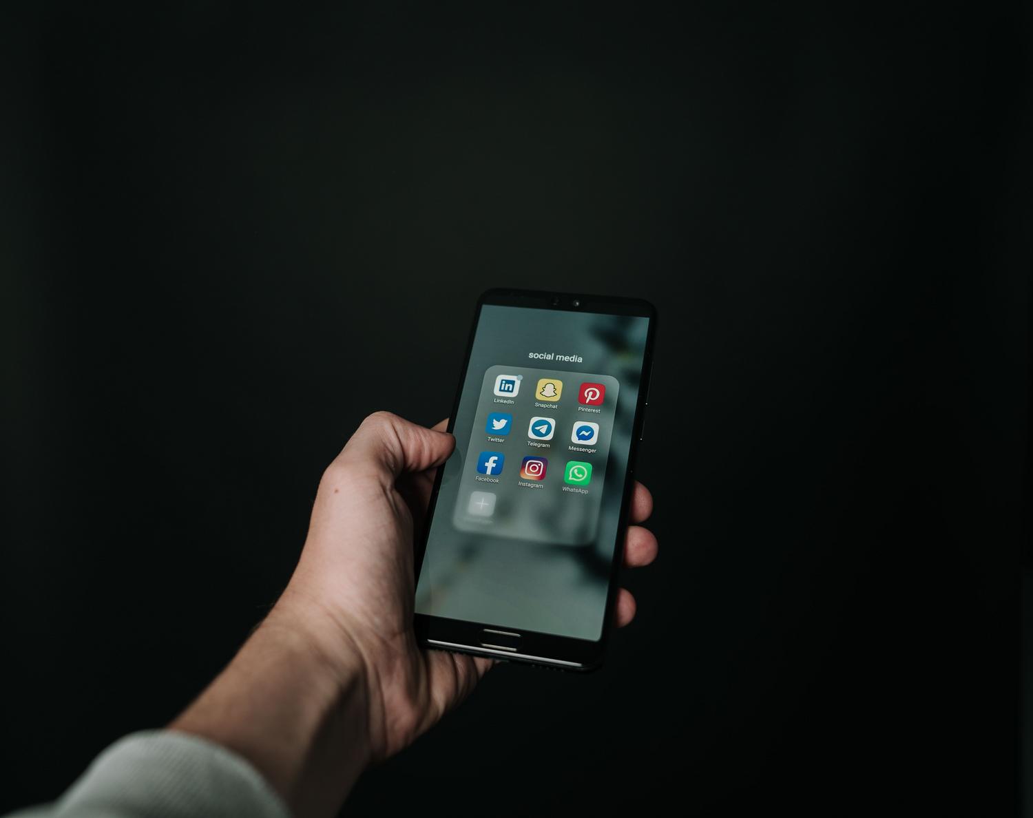 Primer plano de un smartphone mostrando una carpeta con diversas aplicaciones de redes sociales