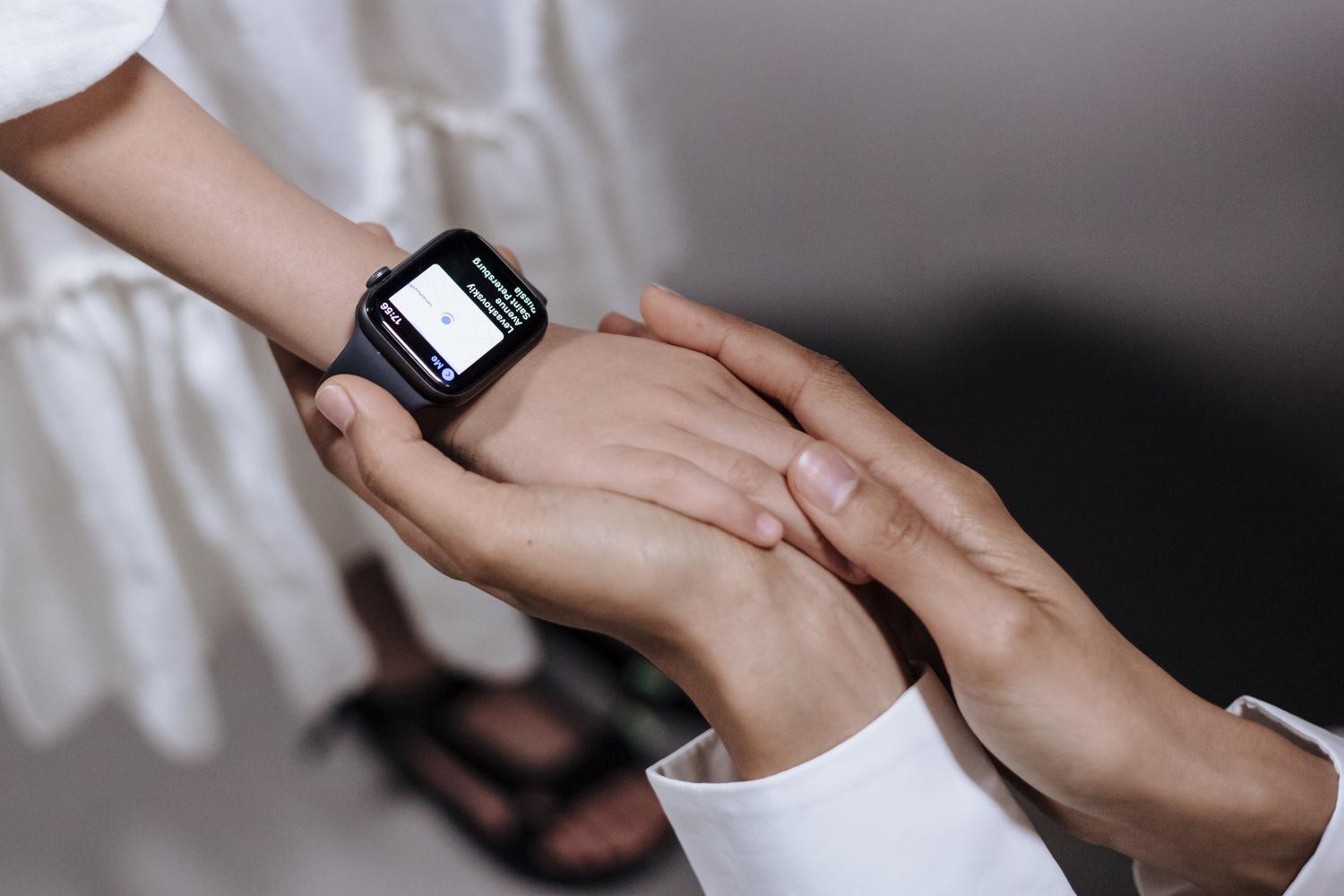 Primer plano de un adulto sosteniendo la mano de un niño que lleva un smartwatch, simbolizando la seguridad familiar y el control parental.