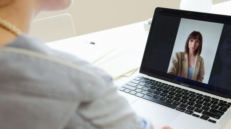 Mujer profesional en una videollamada desde un espacio de trabajo moderno y luminoso, representando un entorno de comunicación seguro y privado.