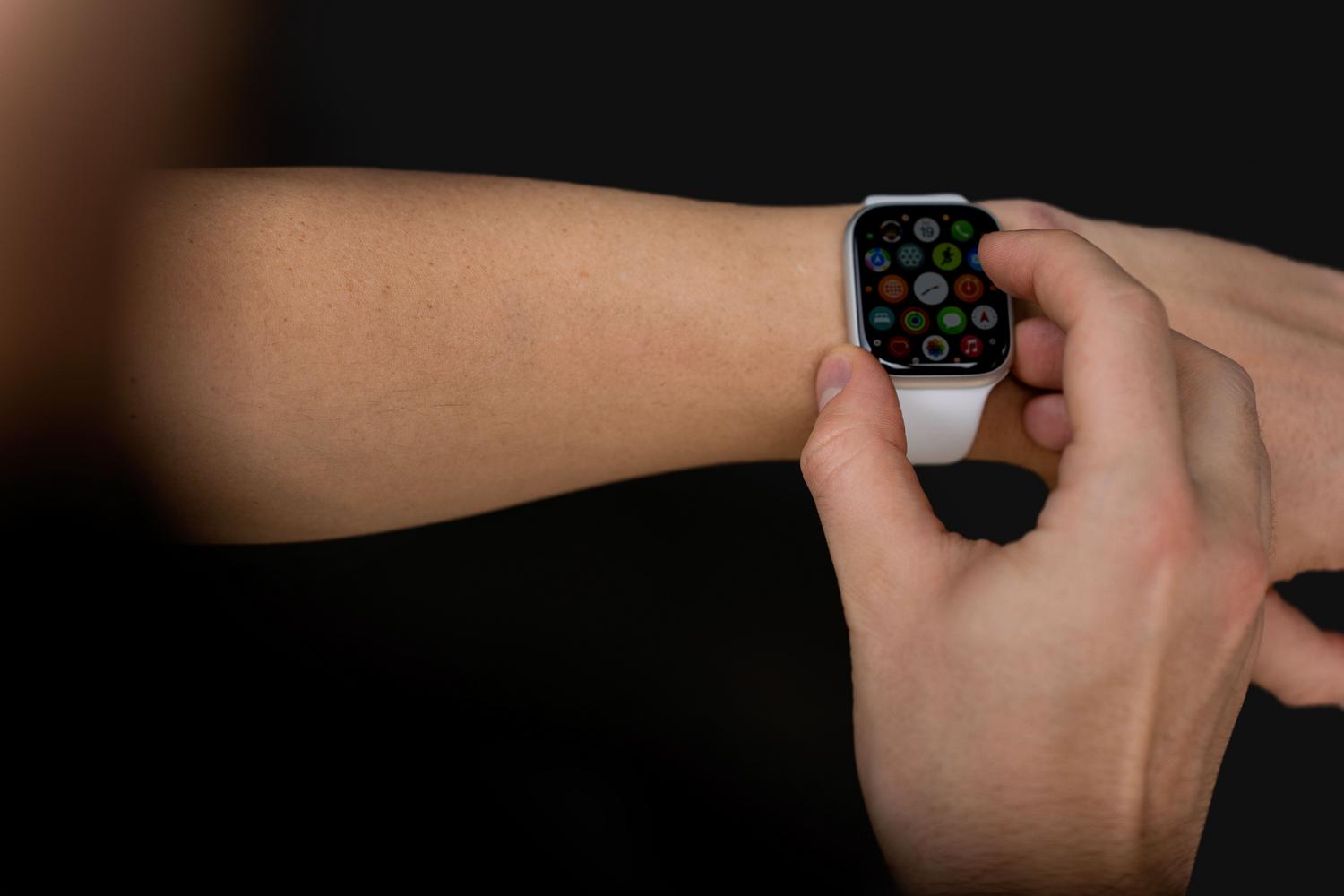 Toma profesional de una mano interactuando con un smartwatch sobre un fondo oscuro, destacando la modernidad y tecnología del dispositivo.