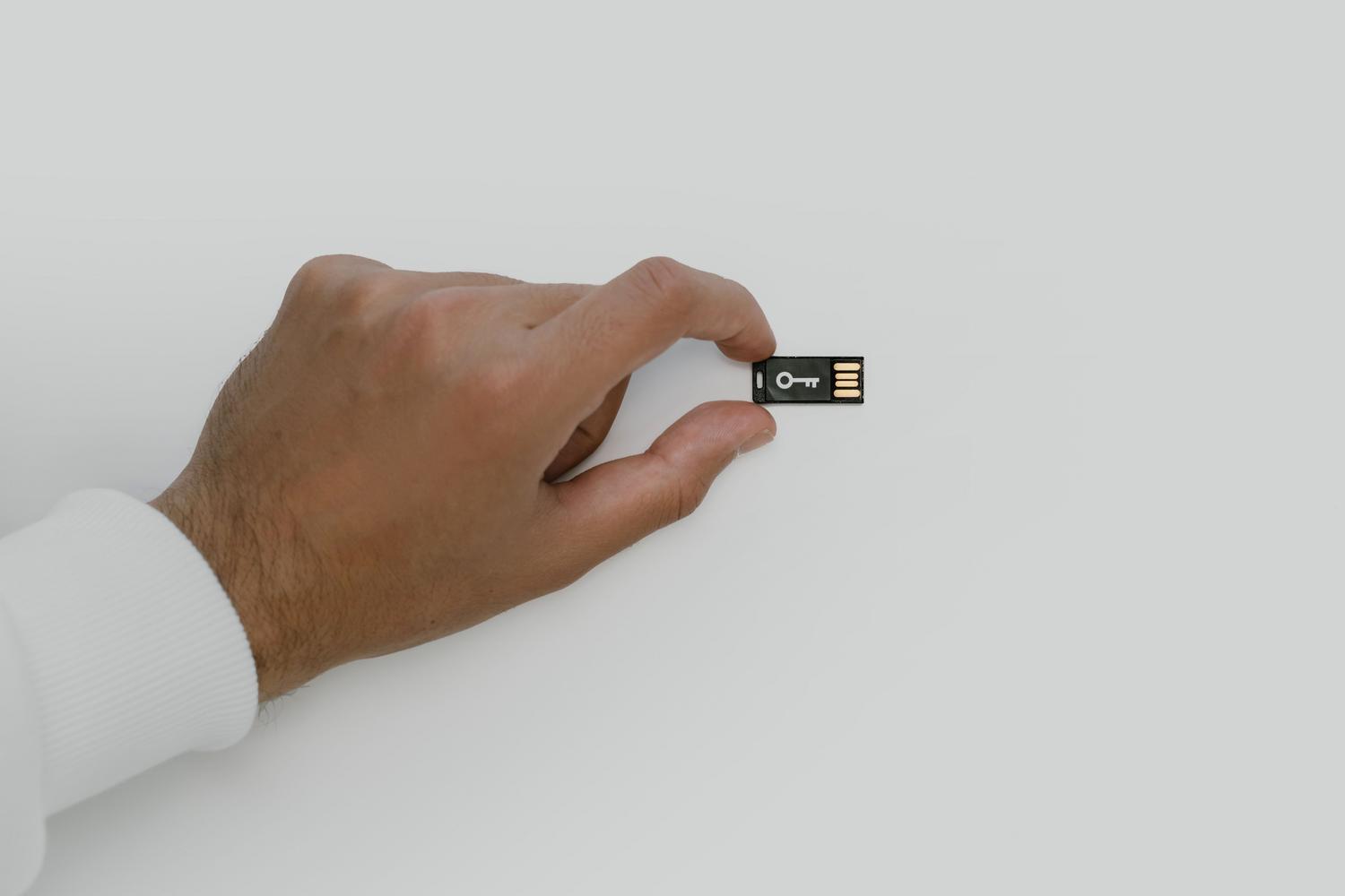 Mano sosteniendo una unidad USB con el símbolo de una llave, simbolizando el cifrado de extremo a extremo y la seguridad de los datos.