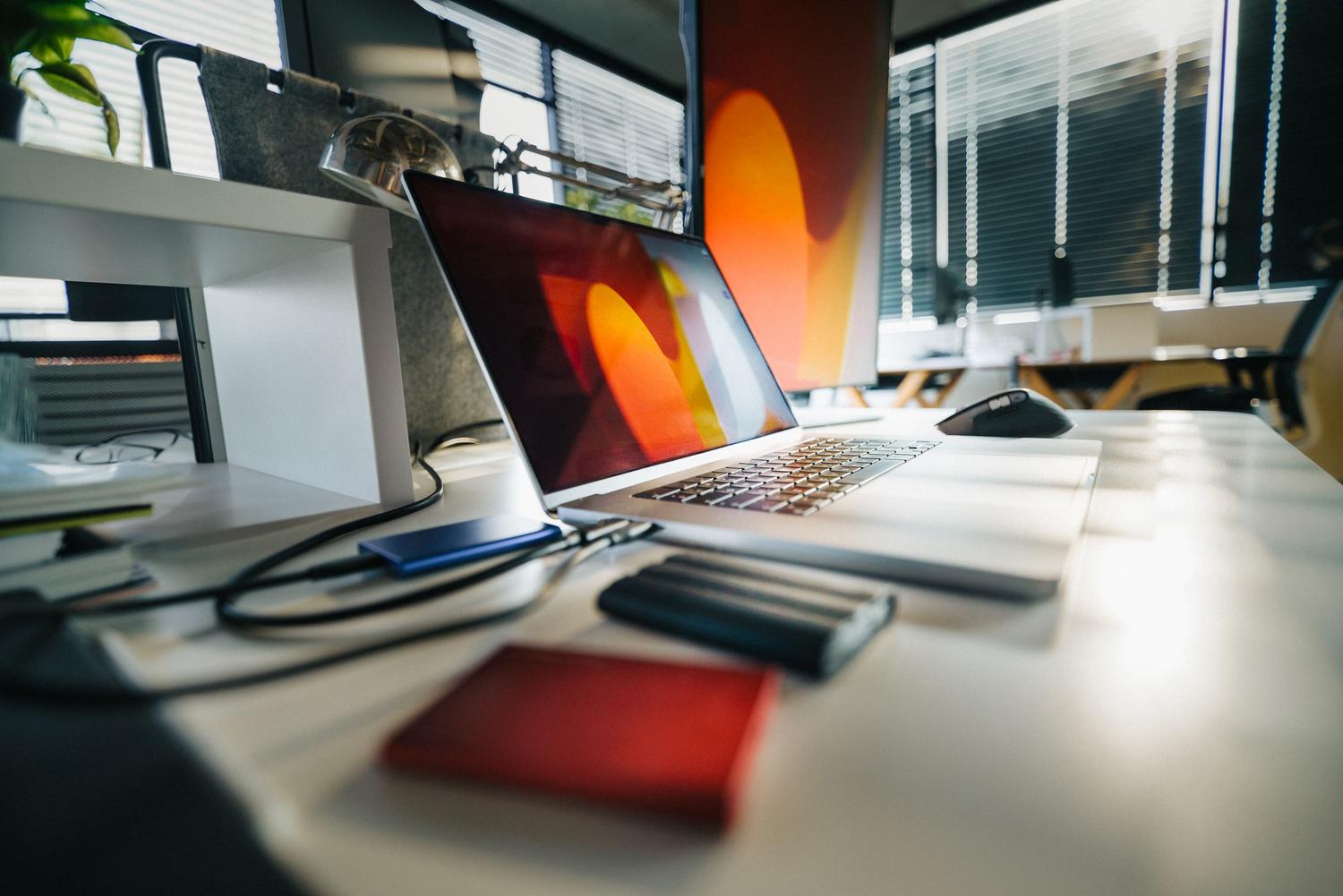 Espacio de trabajo moderno con ordenador portátil y unidades de almacenamiento externas sobre un escritorio.