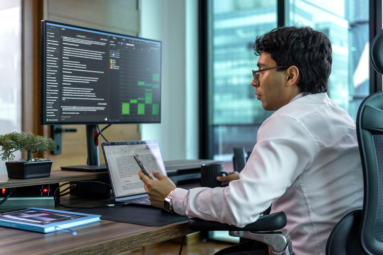 Un hombre concentrado trabajando con múltiples monitores en una oficina, representando la productividad avanzada y el flujo de trabajo digital.