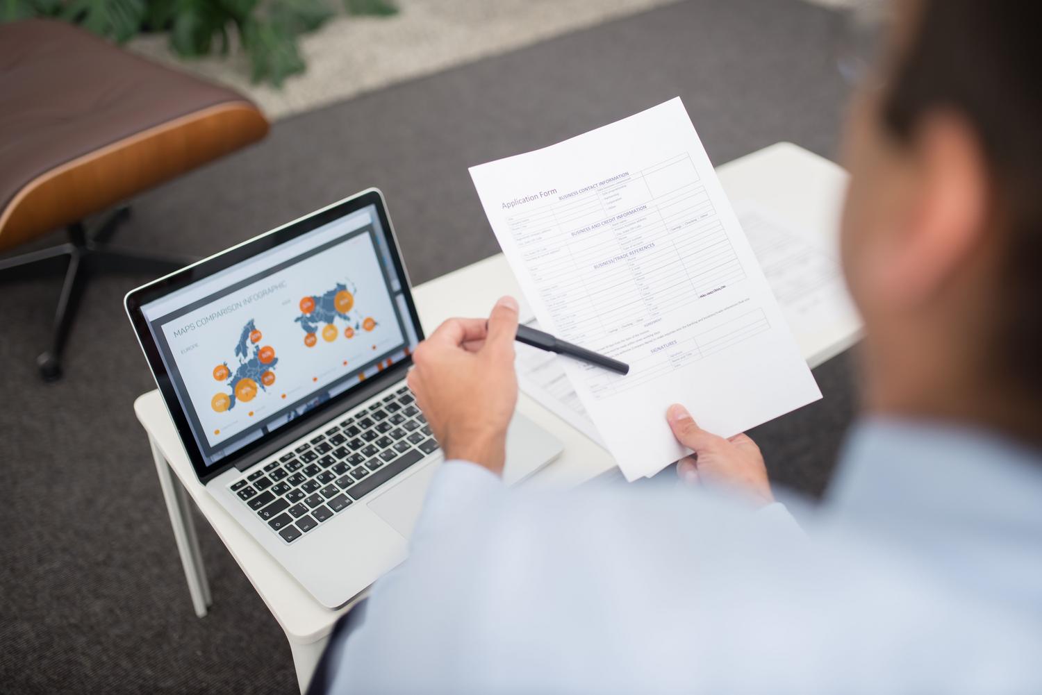 Un hombre de negocios revisando documentos digitales en un portátil, ideal para ilustrar el análisis de contratos o informes financieros.