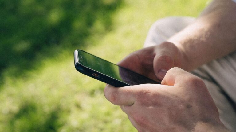 Persona utilizando un smartphone Android al aire libre, representando la sincronización de contactos móvil.