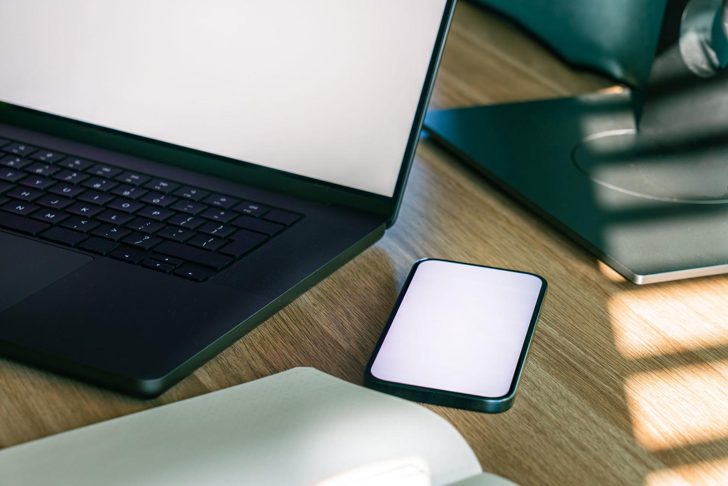 Modern workspace with a laptop and smartphone, illustrating the synchronization of data between devices.