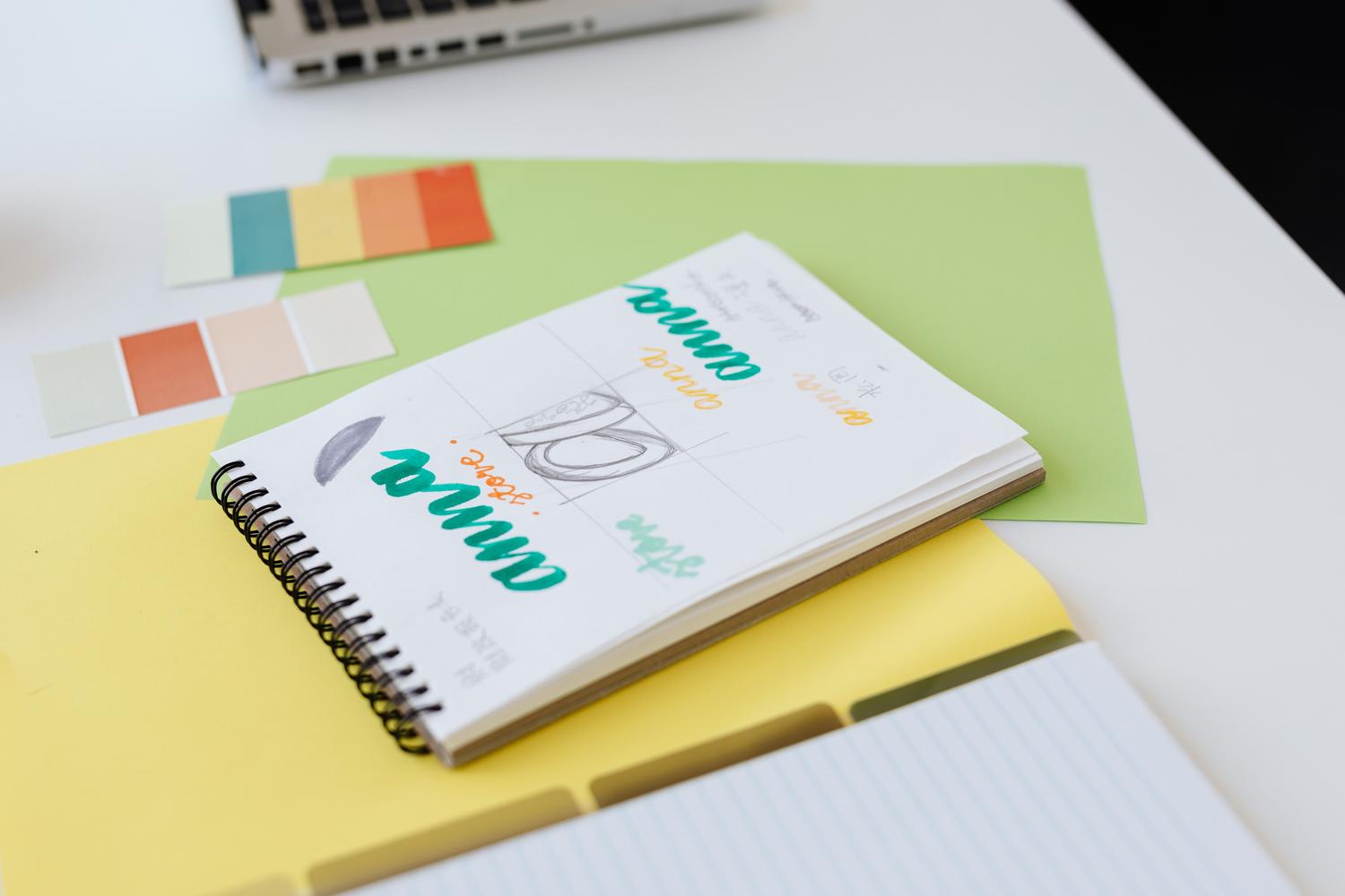 Bocetos de diseño y muestras de colores corporativos sobre un escritorio blanco