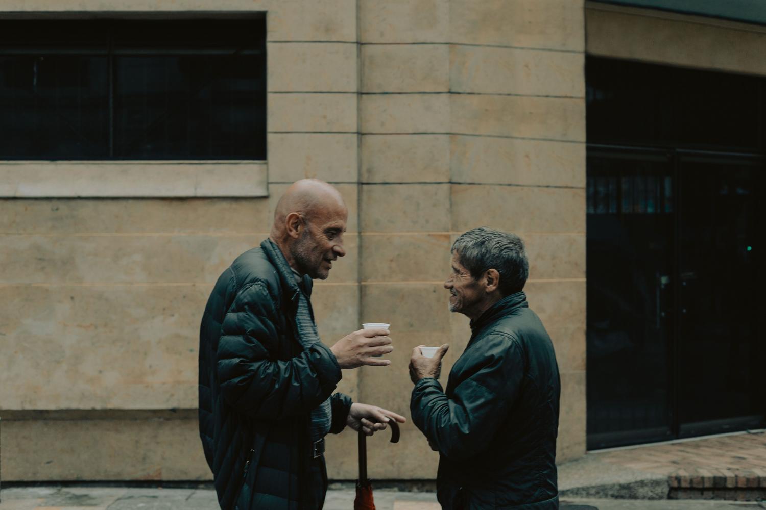 Dos personas locales conversando animadamente en una calle, representando la meta final: la comunicación efectiva con los lugareños.