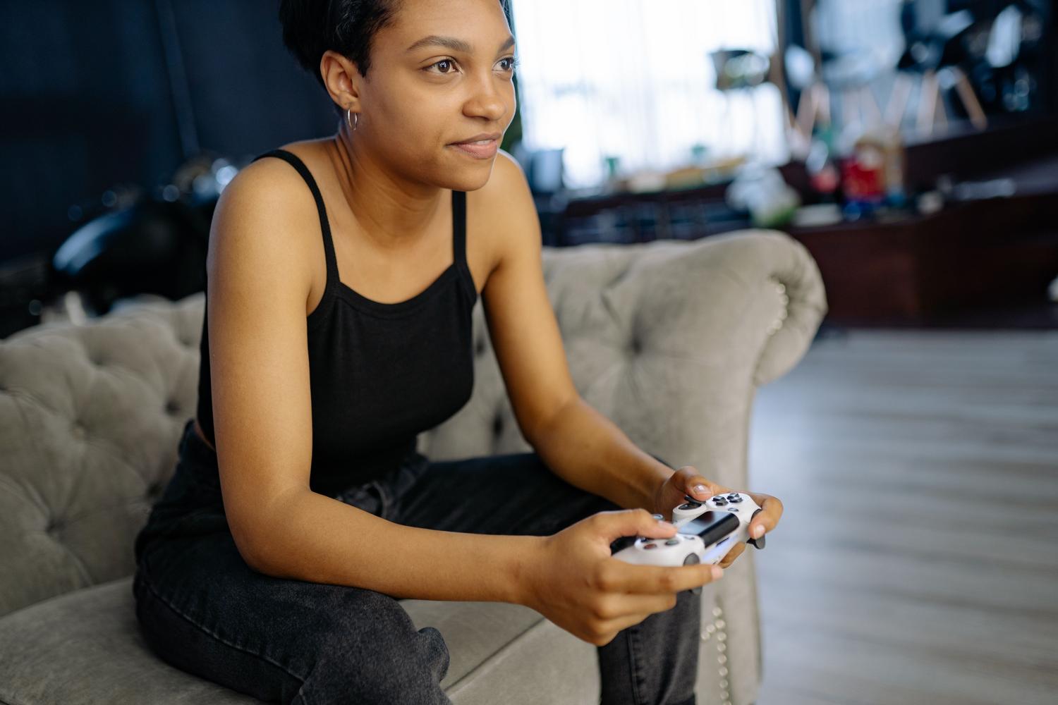 Mujer jugando cómodamente en un sofá con un mando de videojuegos, ilustrando la experiencia de jugar desde cualquier rincón del hogar.
