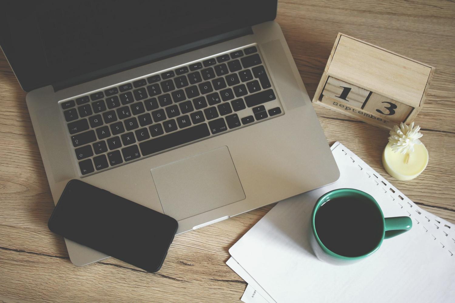 Entorno de trabajo moderno con portátil, café y calendario, ideal para la planificación de proyectos.