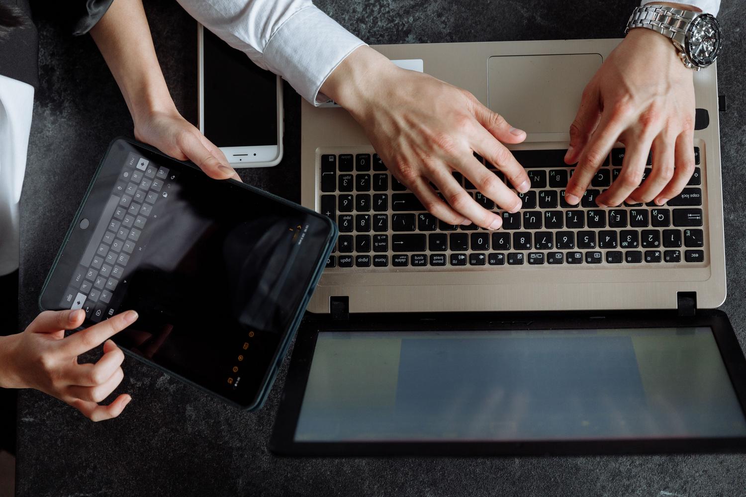 Vista superior de profesionales utilizando un portátil y una tablet, destacando la versatilidad de los componentes de Loop en diferentes dispositivos.