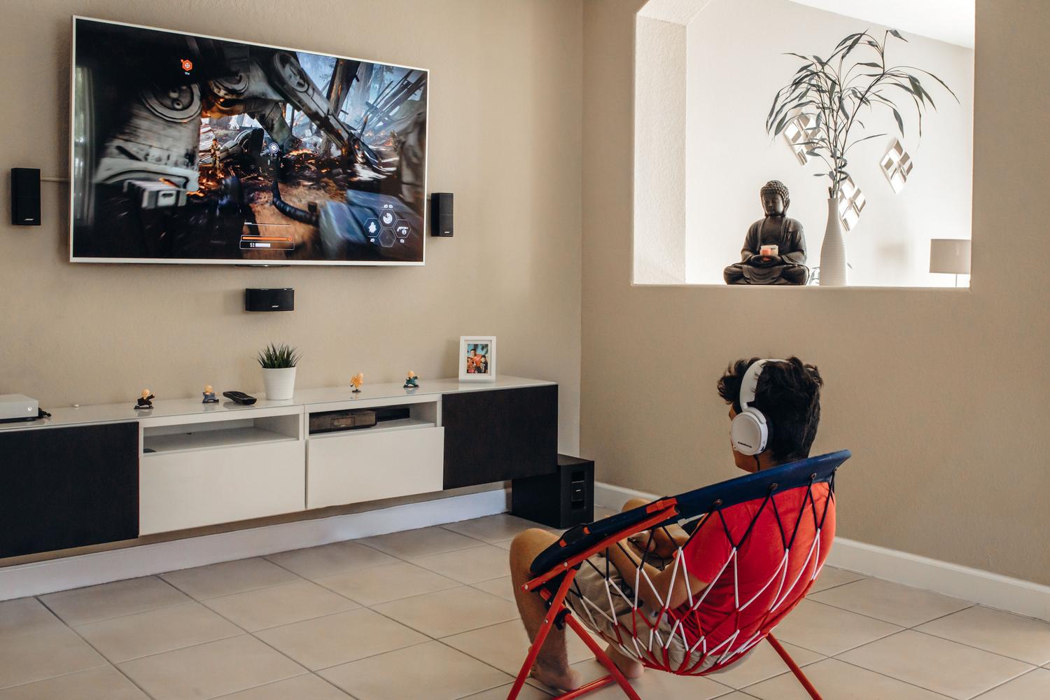Joven disfrutando de videojuegos en un salón moderno con setup de alta gama
