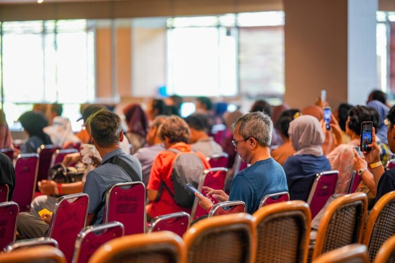 Grupo de personas utilizando sus dispositivos móviles en un evento, representando la comunicación masiva en un grupo de WhatsApp.