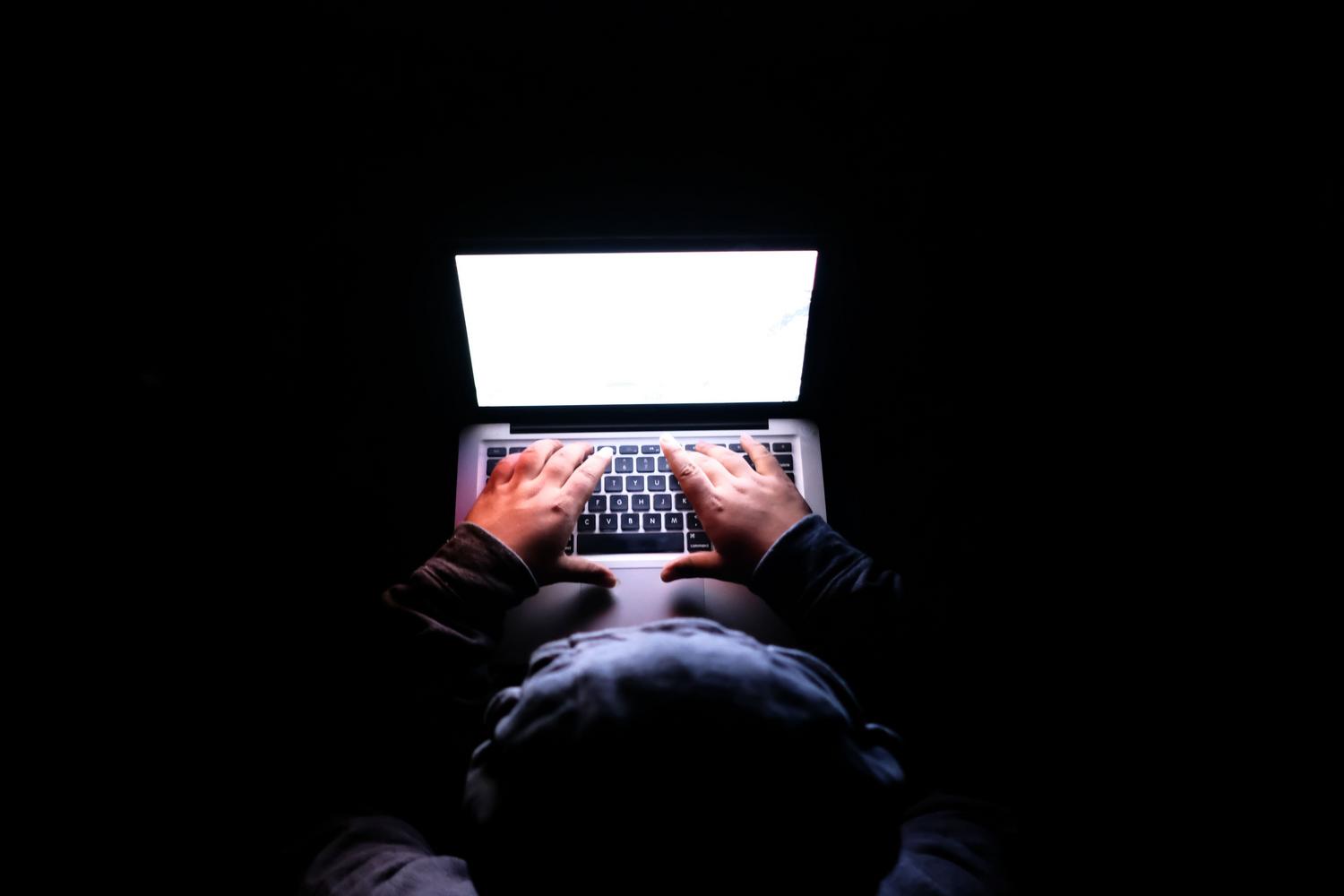 Ich arbeite mit lokaler künstlicher Intelligenz in einem privaten Umfeld. Eine Person arbeitet in einer dunklen und privaten Umgebung mit einem Laptop, was Assoziationen mit Cybersicherheit und lokaler Entwicklung weckt.